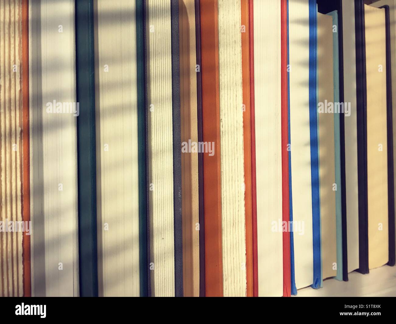 Generic books on a shelf with shadows. - Smartphone Captured Stock Image