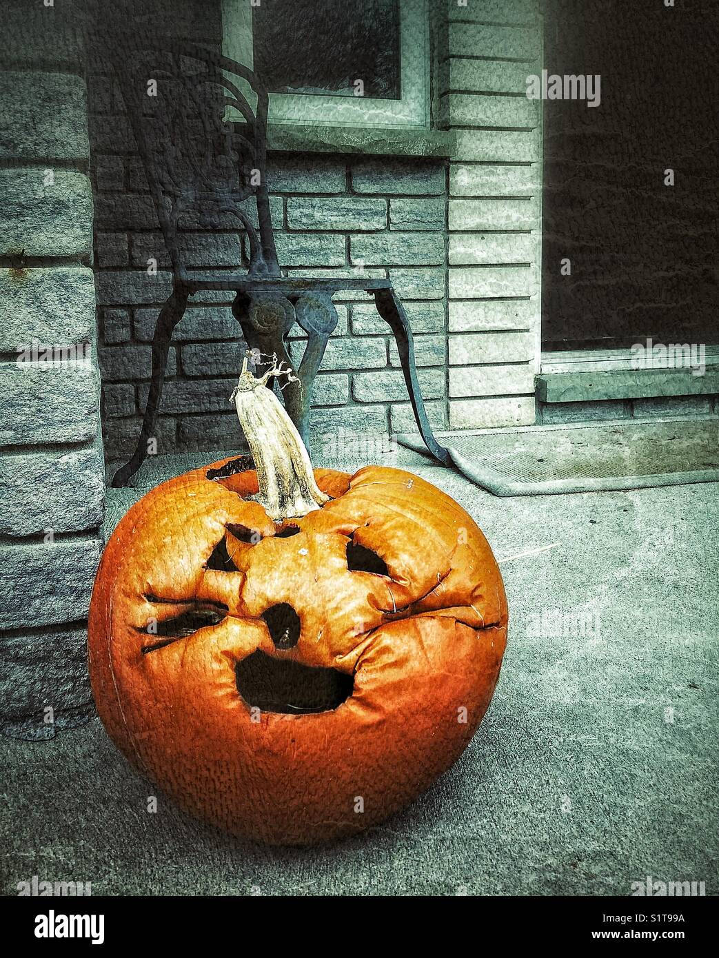Halloween pumpkin (jack-o-lantern) rotting on house doorstep weeks after Halloween - Smartphone Captured Stock Image