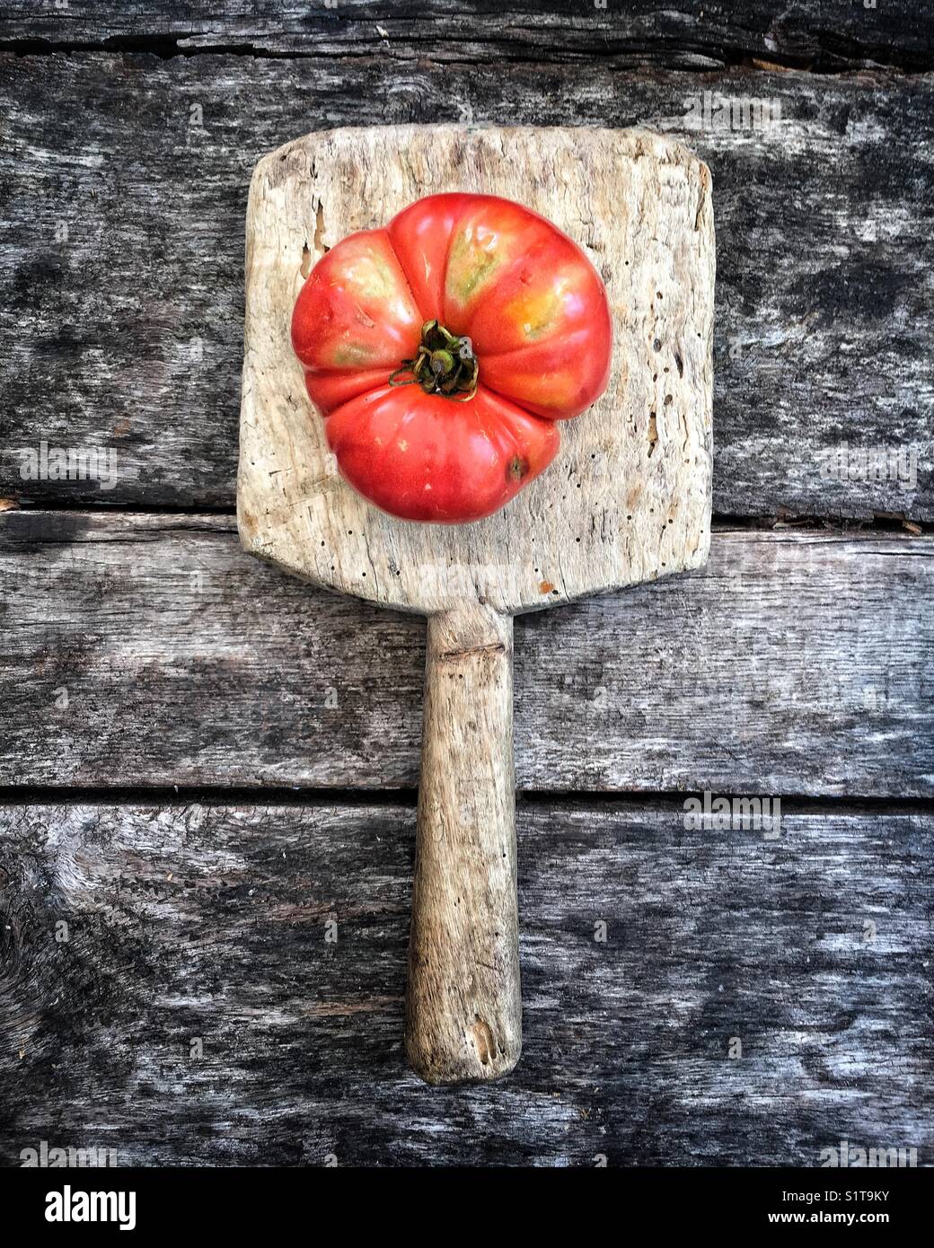 Heirloom tomato on vintage cutting board Stock Photo