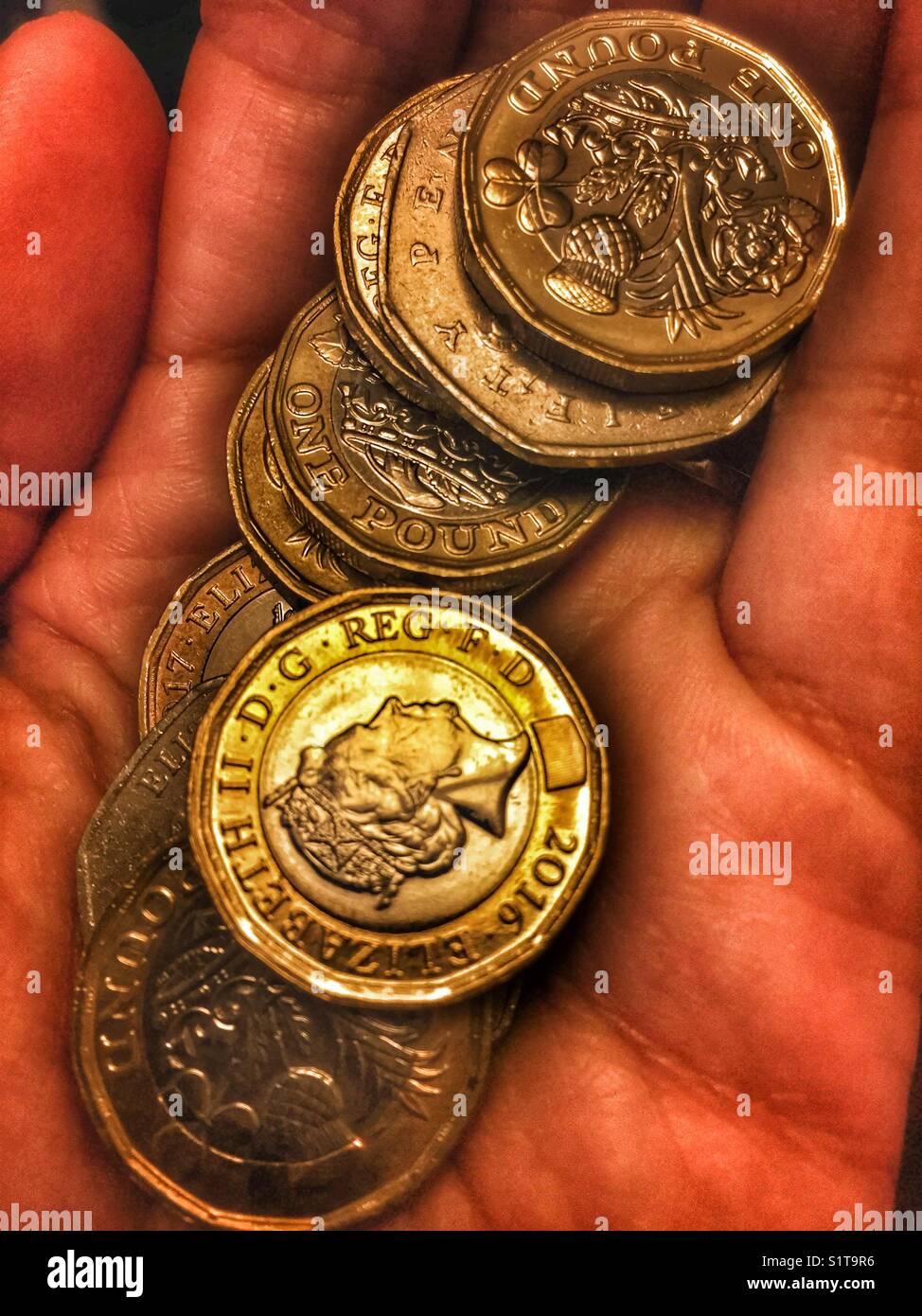Hand holding British coins, pound coins and fifty pence pieces - Smartphone Captured Stock Image