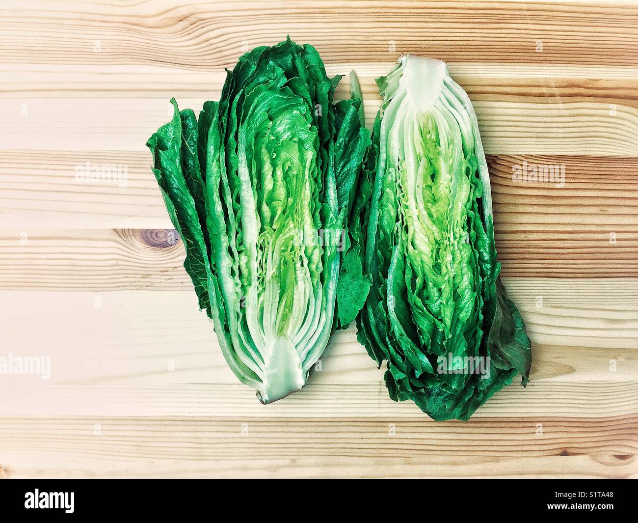 Romaine lettuce cut in half on wooden board Stock Photo
