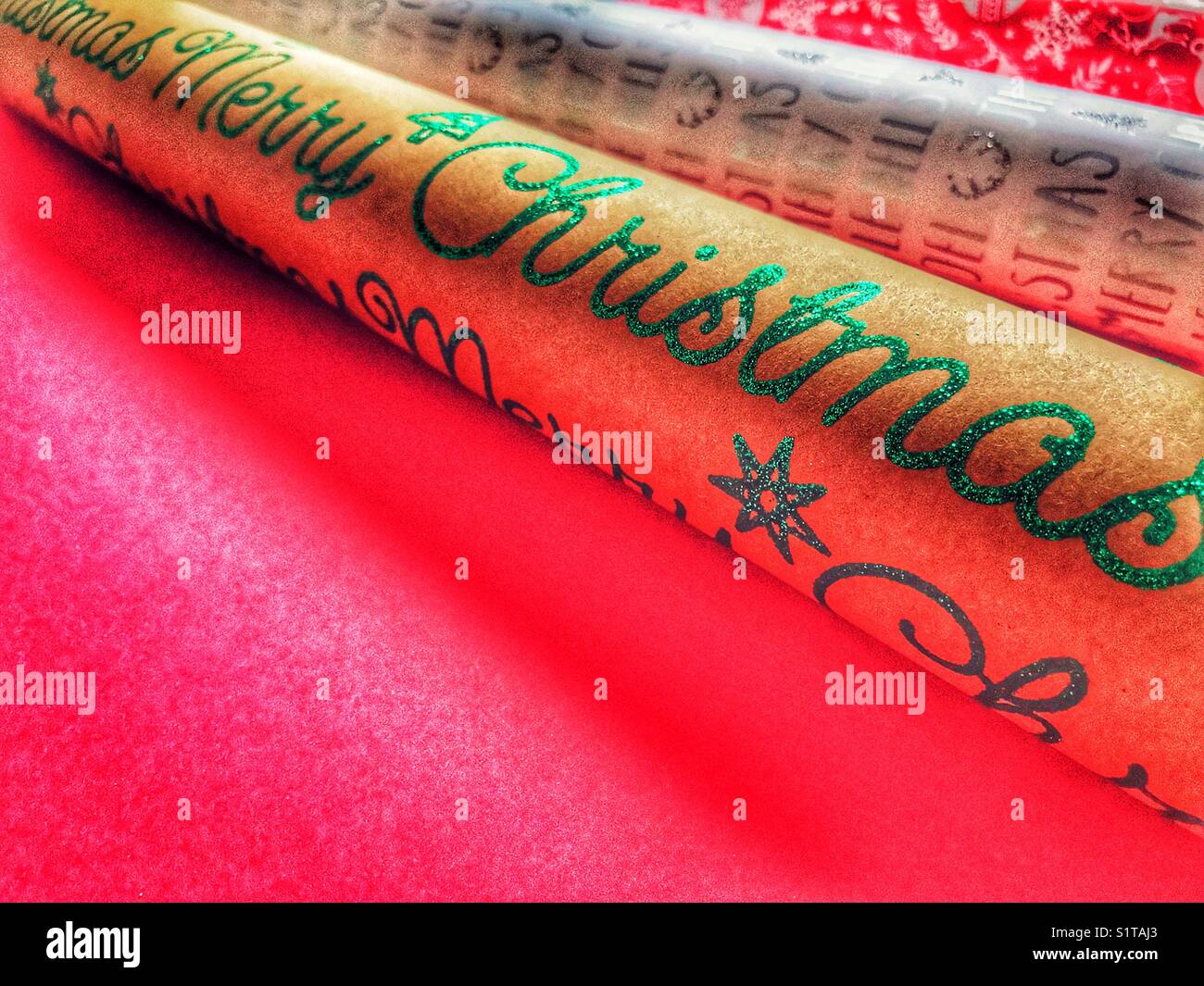Rolls of Christmas wrapping paper on red with copy space - Smartphone Captured Stock Image