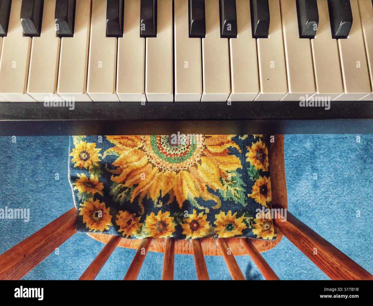 Keyboard and chair with sunflower tapestry cushion, high angle view - Smartphone Captured Stock Image
