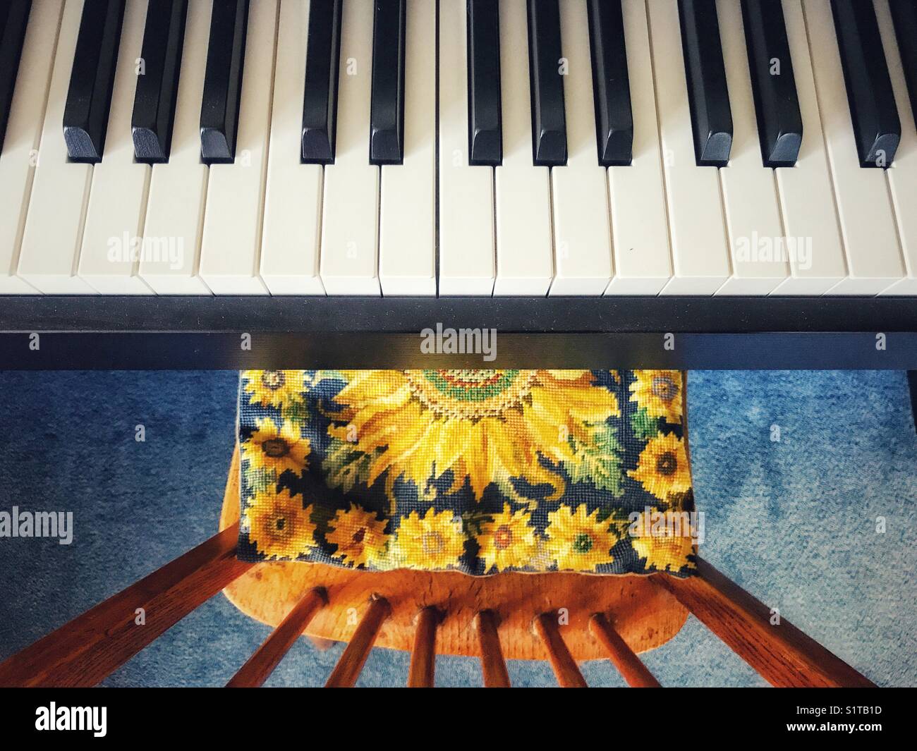 Keyboard and chair with sunflower tapestry cushion, high angle view - Smartphone Captured Stock Image