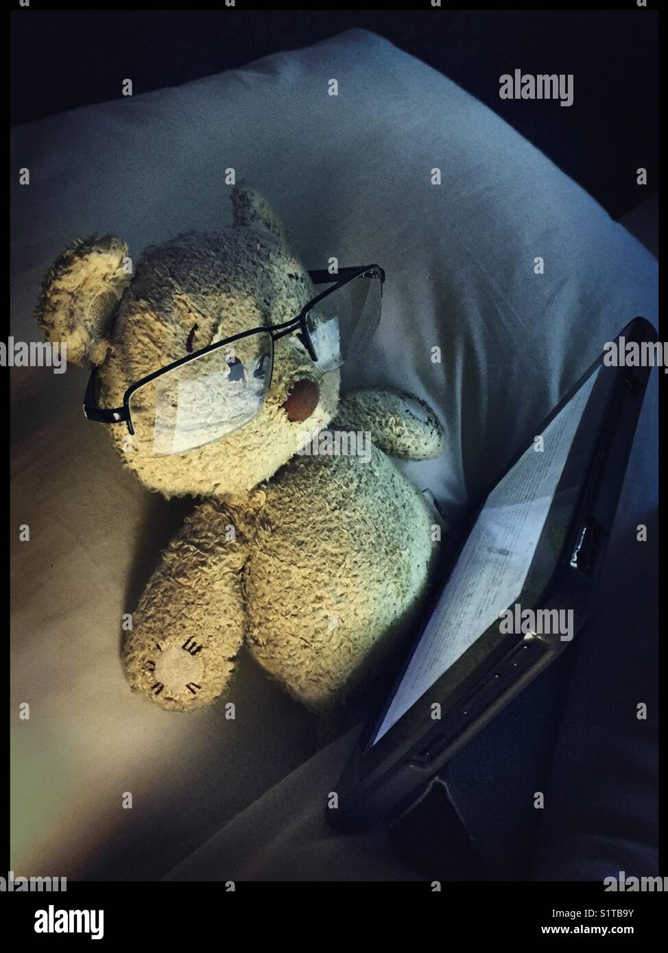 Reading a mobile device or tablet in bed -blue light, good night sleep.  Coronavirus working from home - Smartphone Captured Stock Image