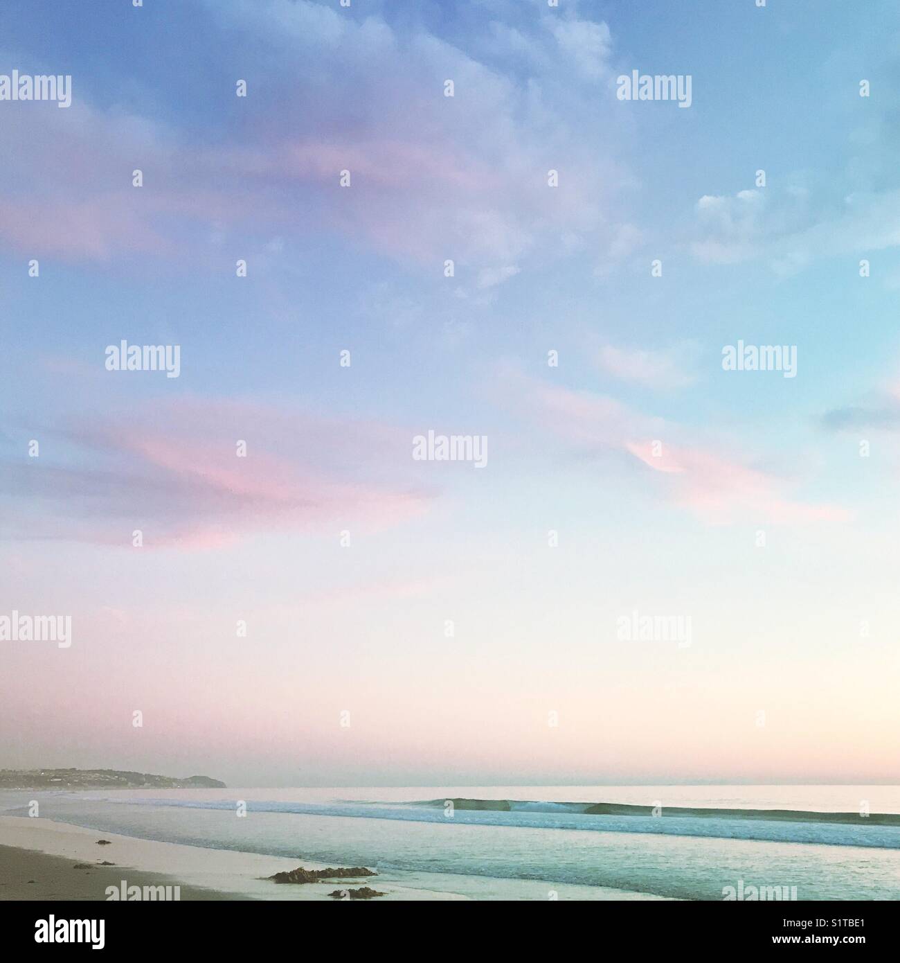 Muted pink and blue pastel sky and ocean beach landscape. Stock Photo