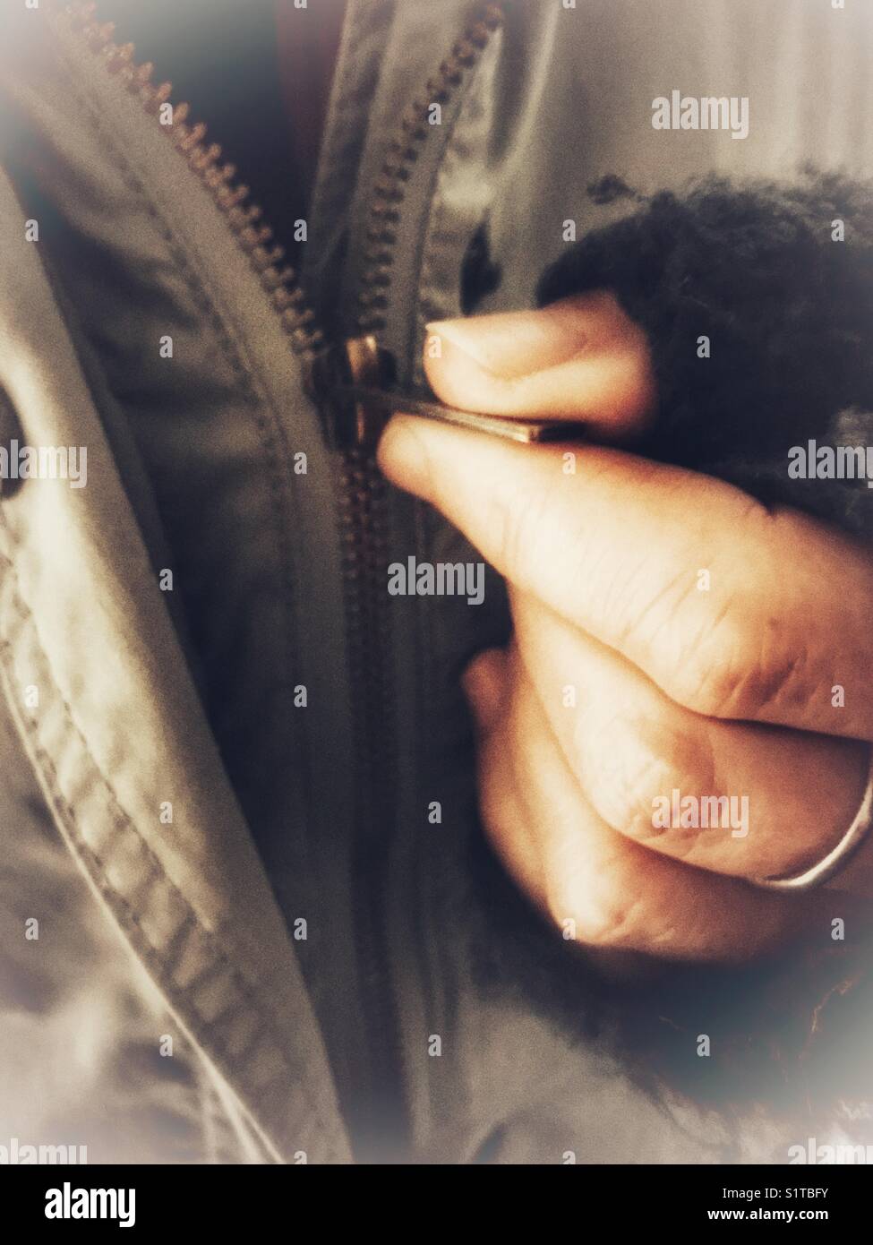 Doing up the zip of a winter jacket - Smartphone Captured Stock Image