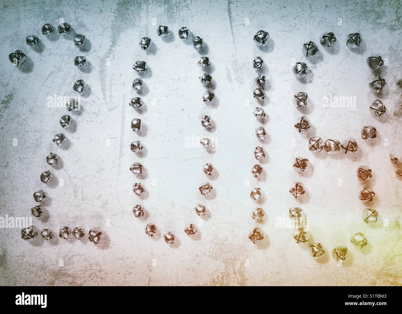 The year 2018 made with small silver bells on a ceramic tile with creative grunge processing - Smartphone Captured Stock Image