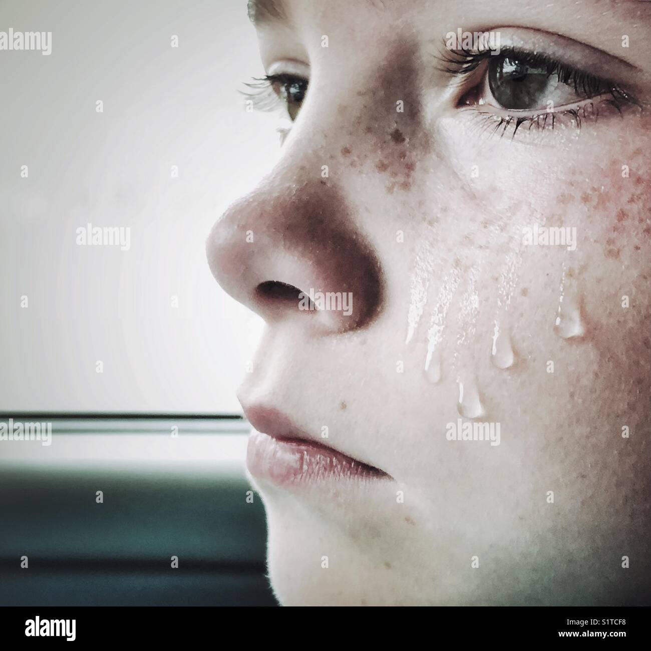 Side view of girl crying with teardrops falling down her cheek Stock Photo