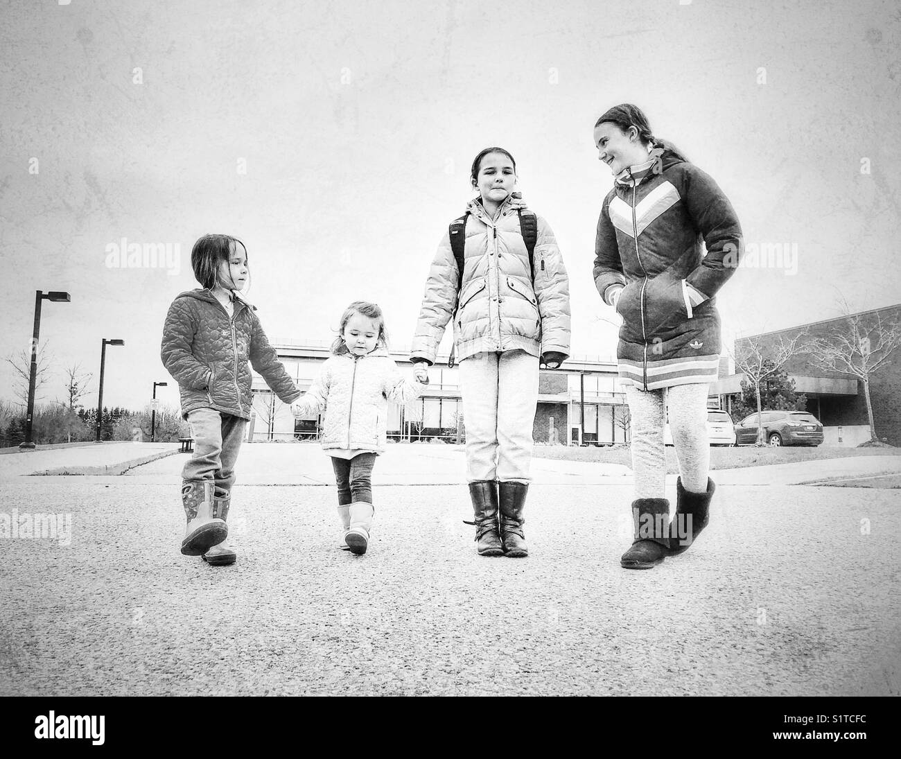 Four girls walking together from a community recreation centre in black and white Stock Photo
