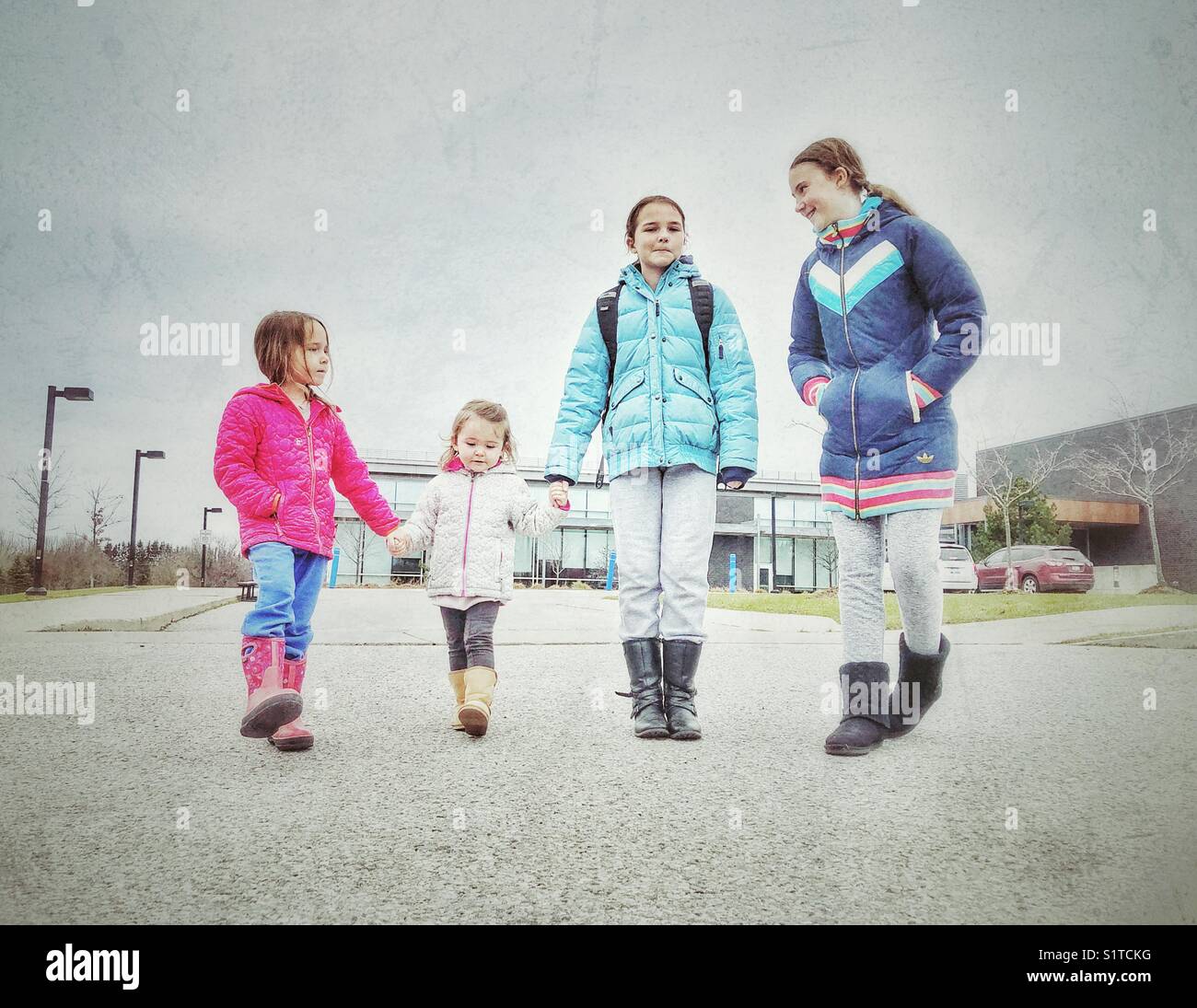 Candid image of four sisters walking and talking together outside of a community recreation centre in Newcastle, Ontario, Canada Stock Photo
