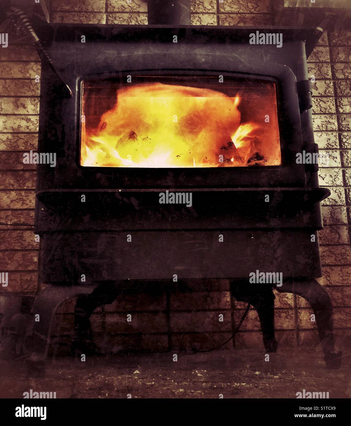 Fire burning in a black wrought iron wood stove with viewing window - Smartphone Captured Stock Image