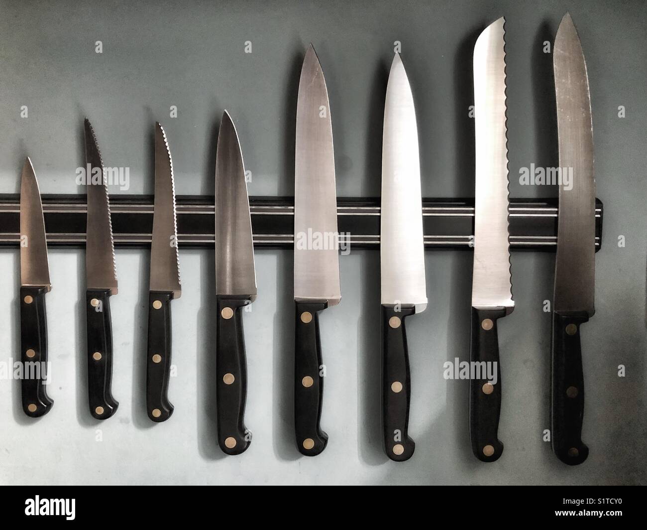 Row of kitchen knives on magnetic rack Stock Photo