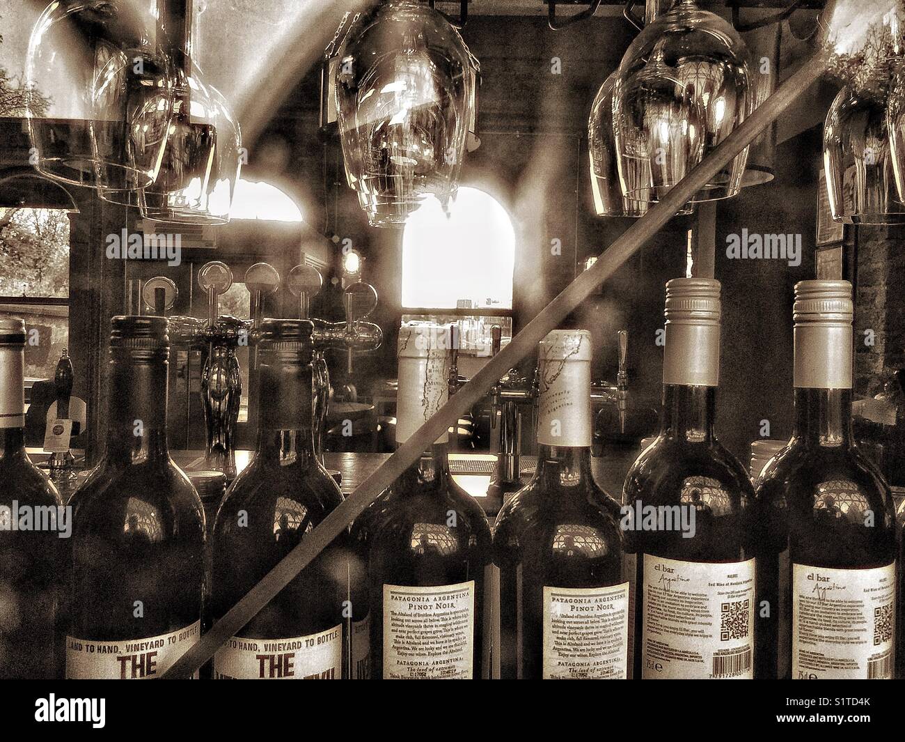 Wine bottles and glass in the window of a bar. - Smartphone Captured Stock Image