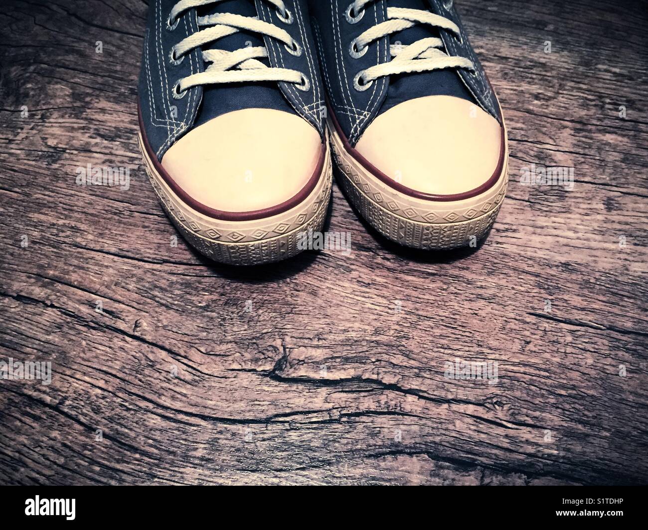 Close up of dark blue canvas sneakers on wooden surface - Smartphone Captured Stock Image
