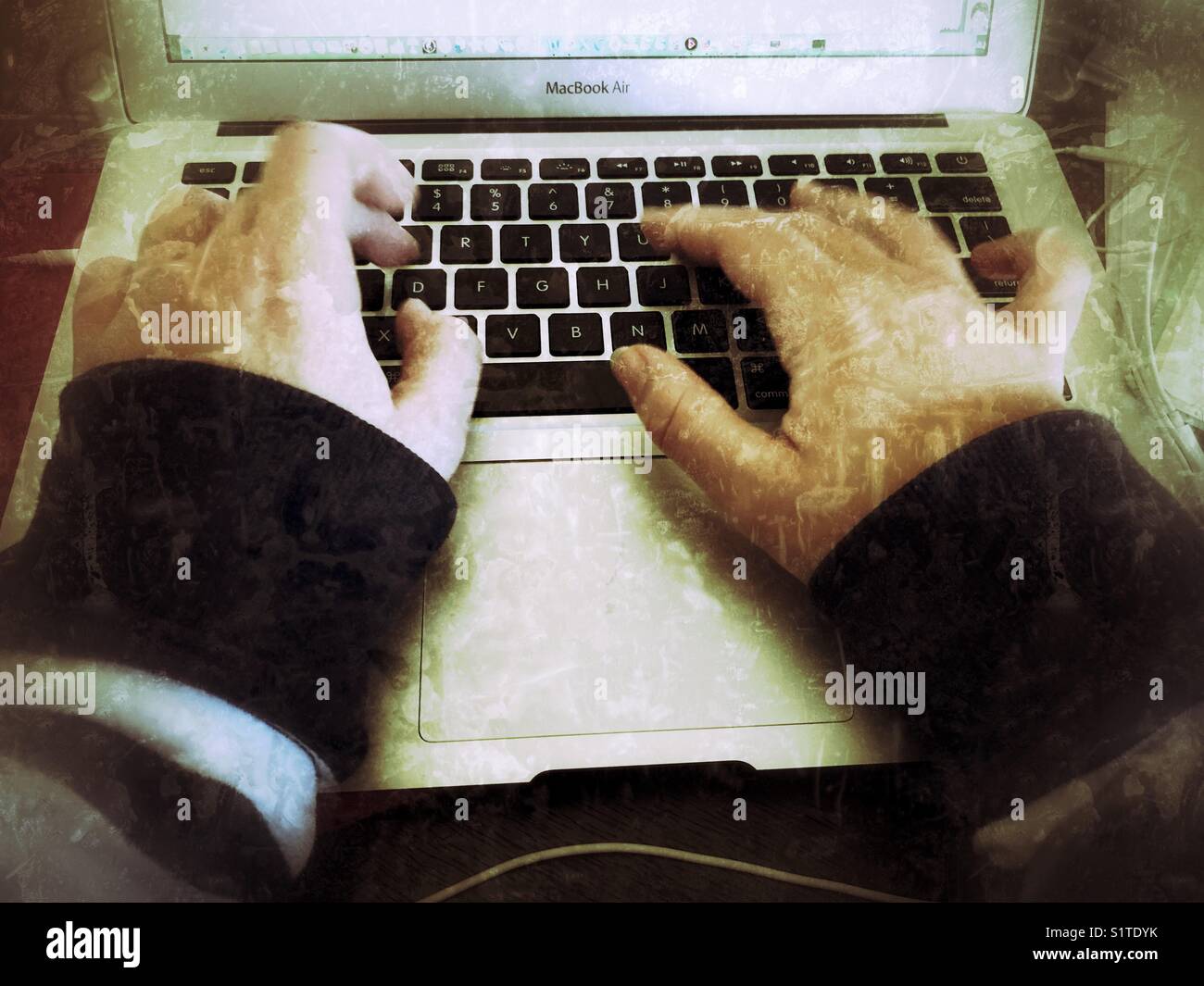 Millennial typing on a laptop keyboard - Smartphone Captured Stock Image
