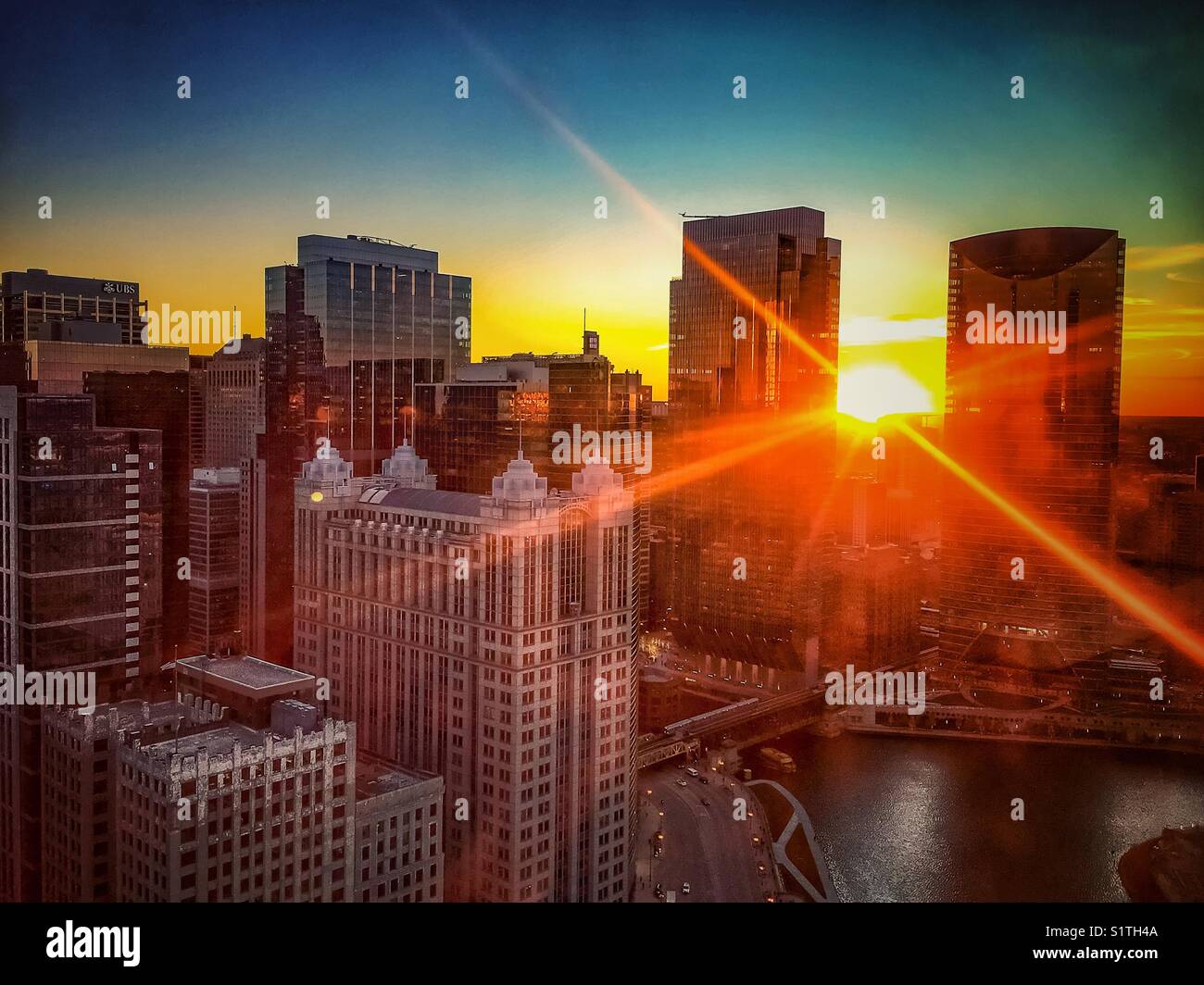 Sunbeams extend over Chicago cityscape at sunset Stock Photo