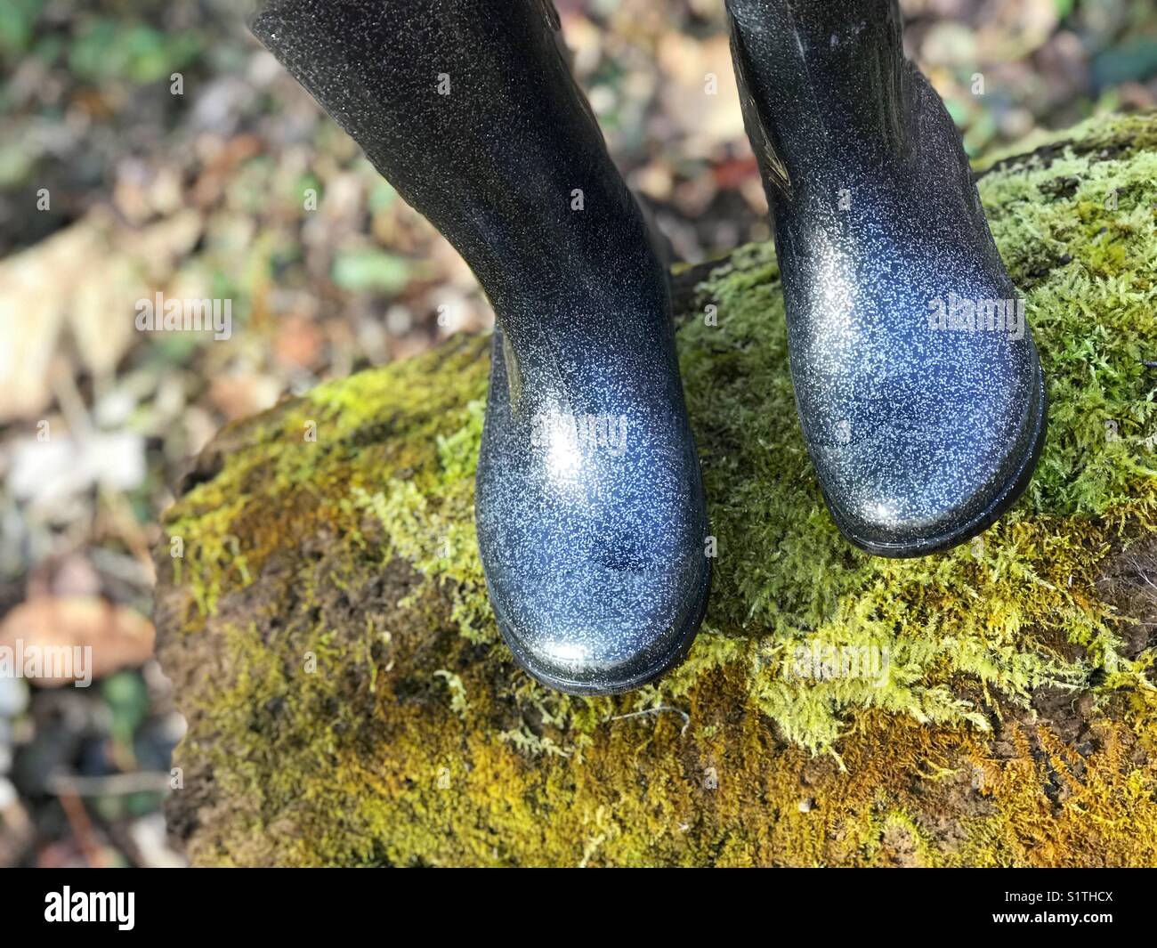 Child’s boots on a mossy log Stock Photo