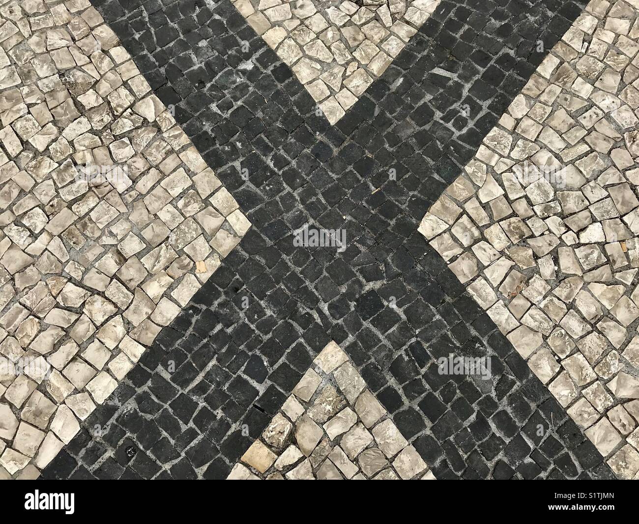 The letter “X” formed by different coloured mosaic tiles on a sidewalk - Smartphone Captured Stock Image
