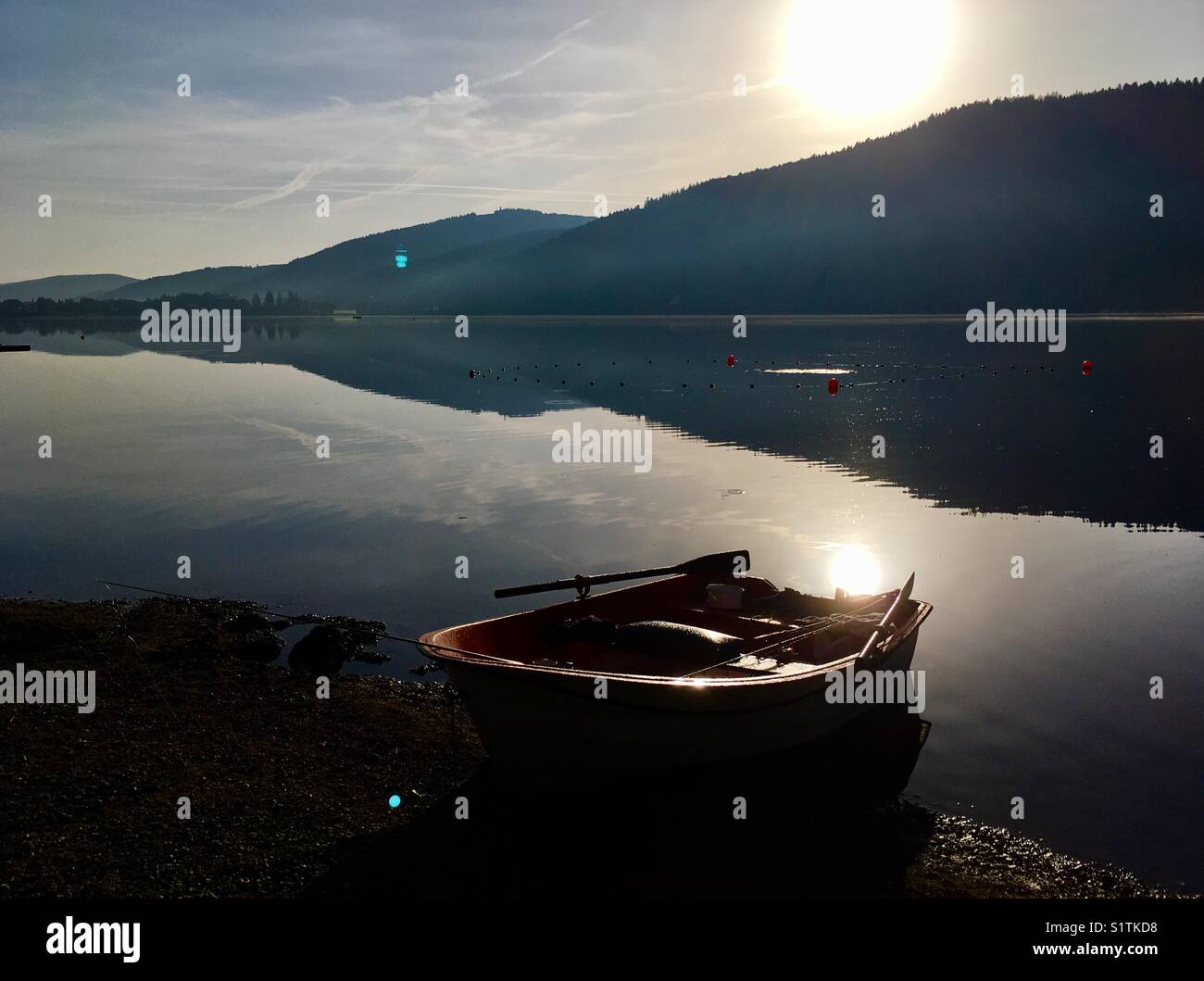 Small rowing boat on the shores of the calm and peaceful Titisee lake in the German Black Forest, in the early morning Stock Photo