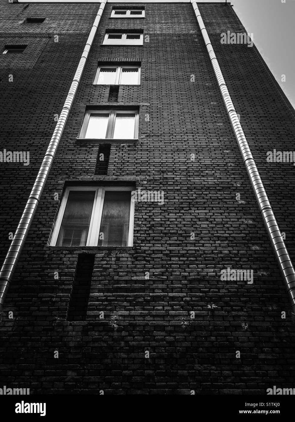 A brick wall with windows and shiny downpipes Stock Photo