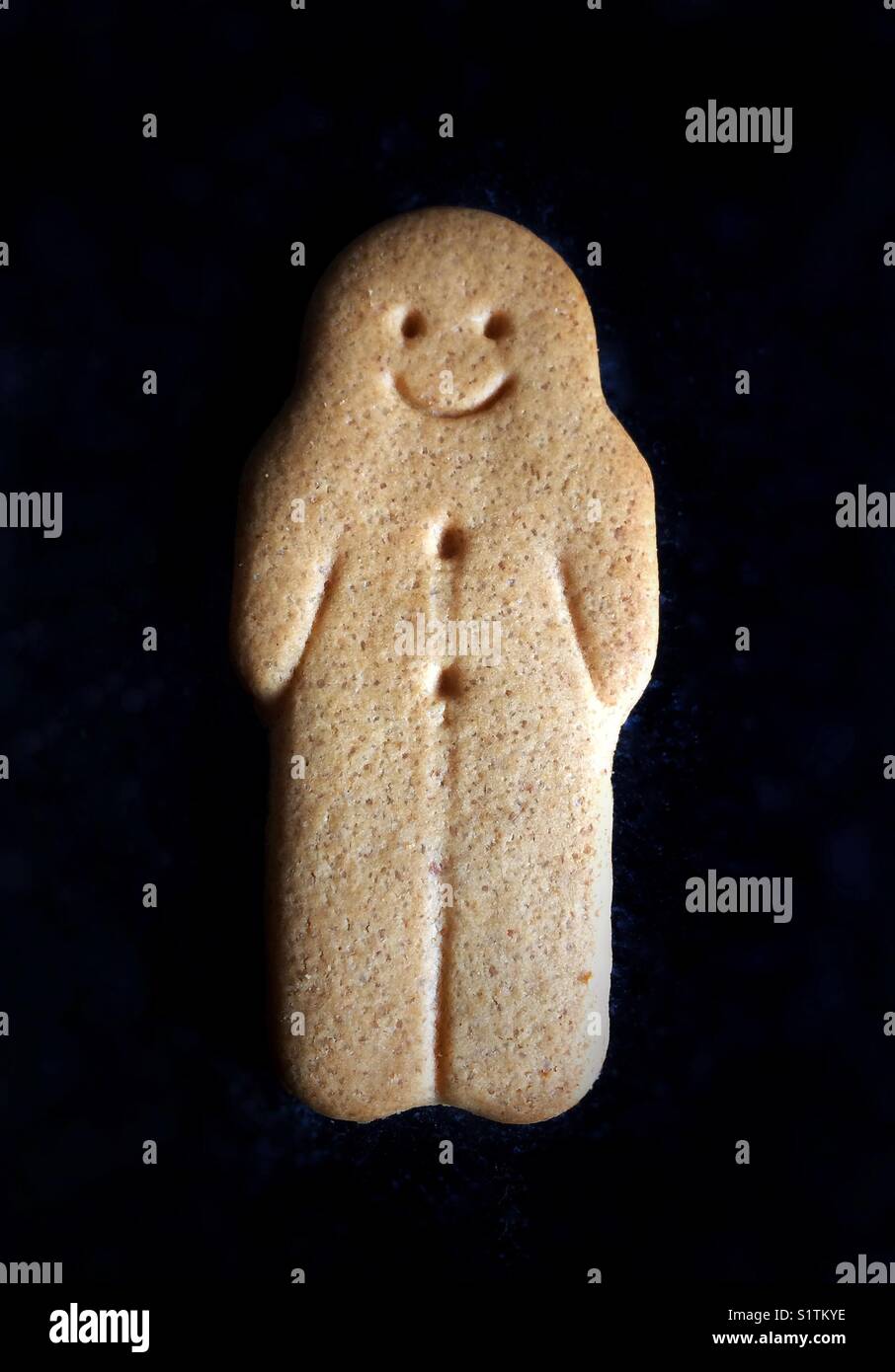 A smiling gingerbread man on a black background - Smartphone Captured Stock Image