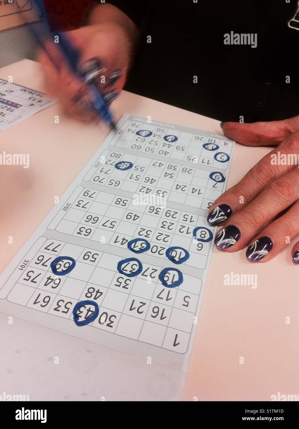 Lady with painted nails, playing bingo. Stock Photo