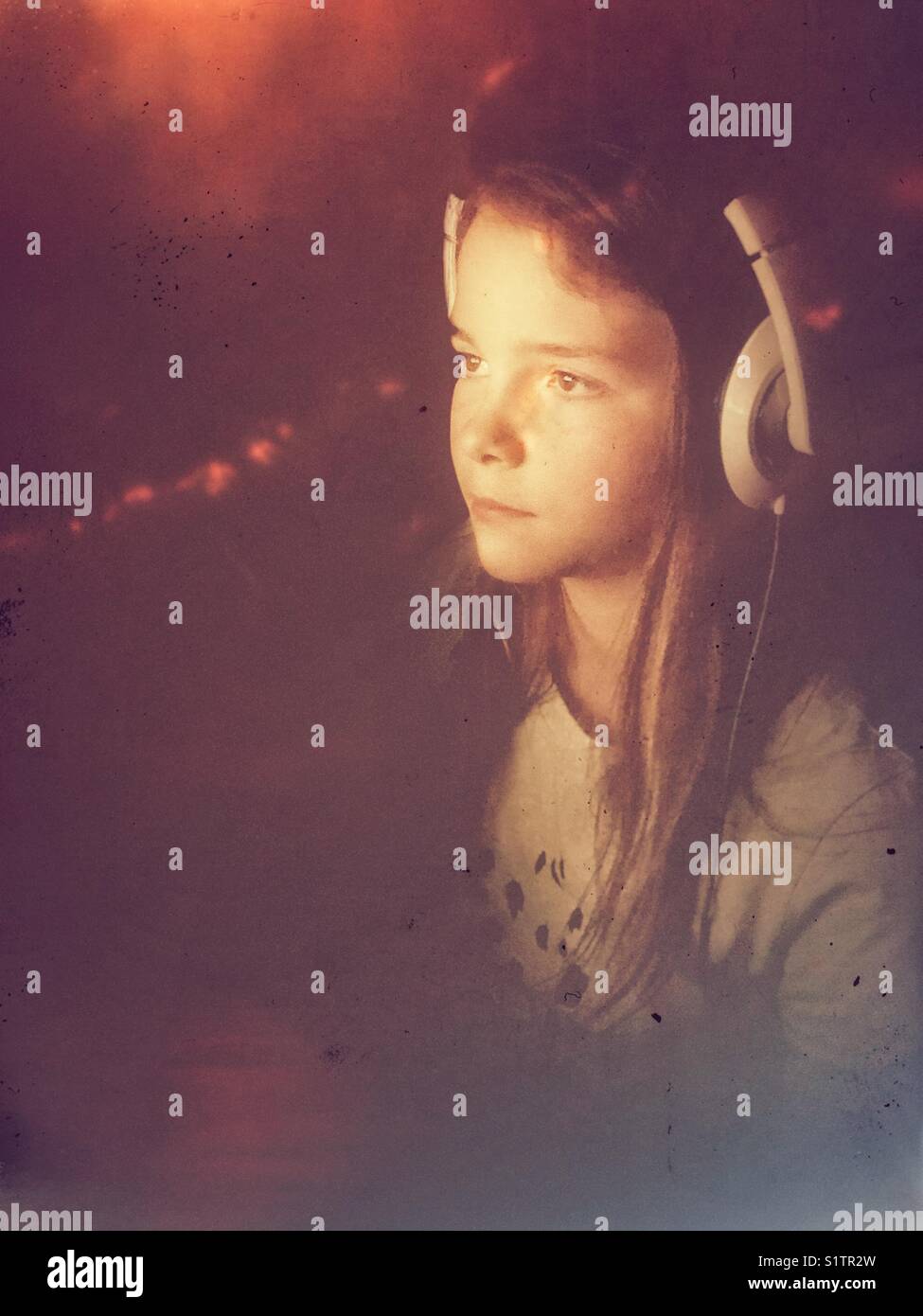 Girl wearing white headphones looking to the side with hazy, surreal light surrounding her - Smartphone Captured Stock Image