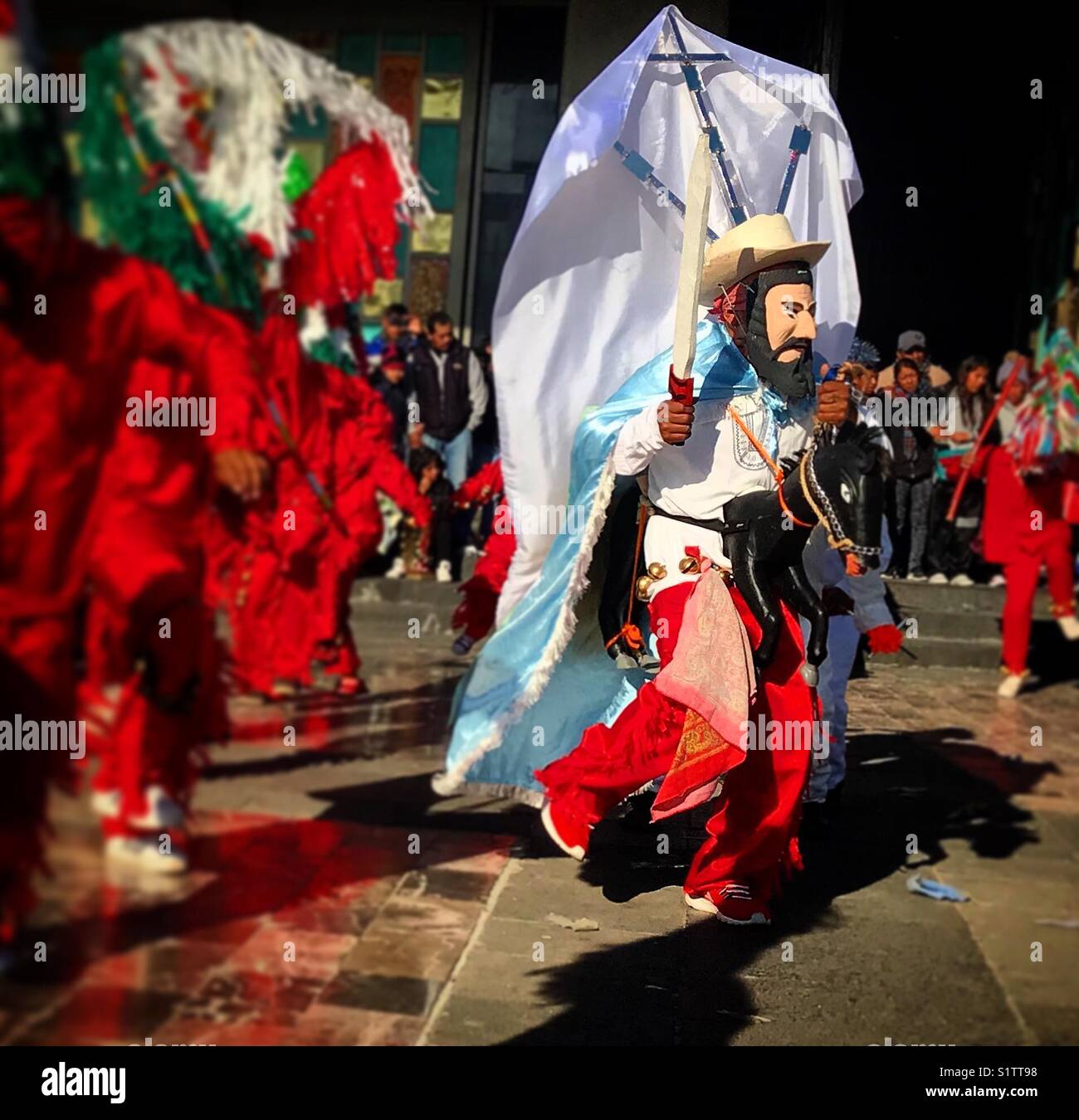 A man dressed as Saint James Apostle riding his horse and holding his sword surrounded by devils dances during Our Lady of Guadalupe pilgrimage in Mexico City Stock Photo