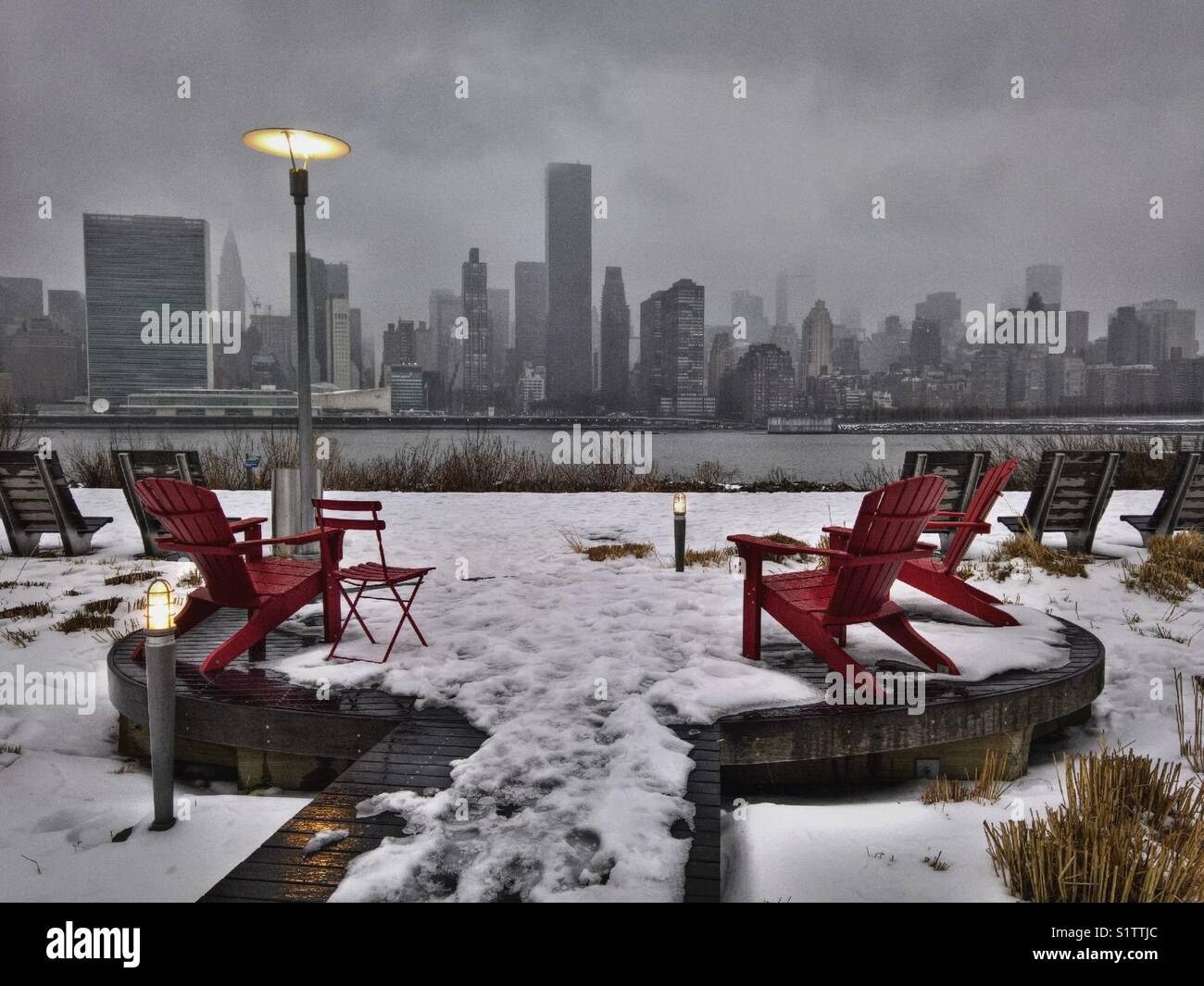 Empty Red chairs on a snowy day at Gantry State Park in Long Island City, facing the East River mad Midtown Manhattan - Smartphone Captured Stock Image
