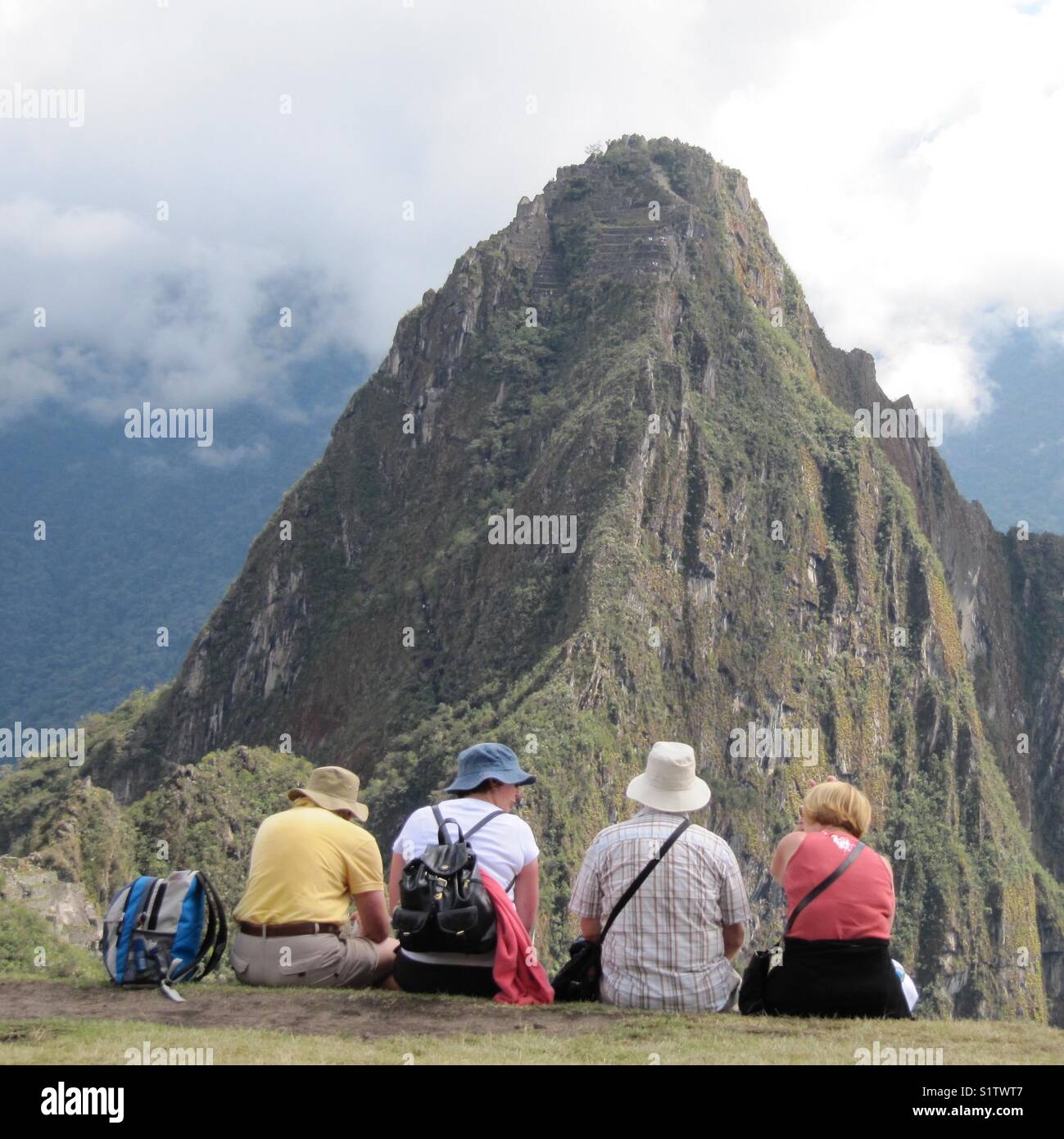 Baby boomers traveling world, enjoying retirement. Senior couples sitting viewing scenic mountain views - Machu Picchu, Peru Stock Photo