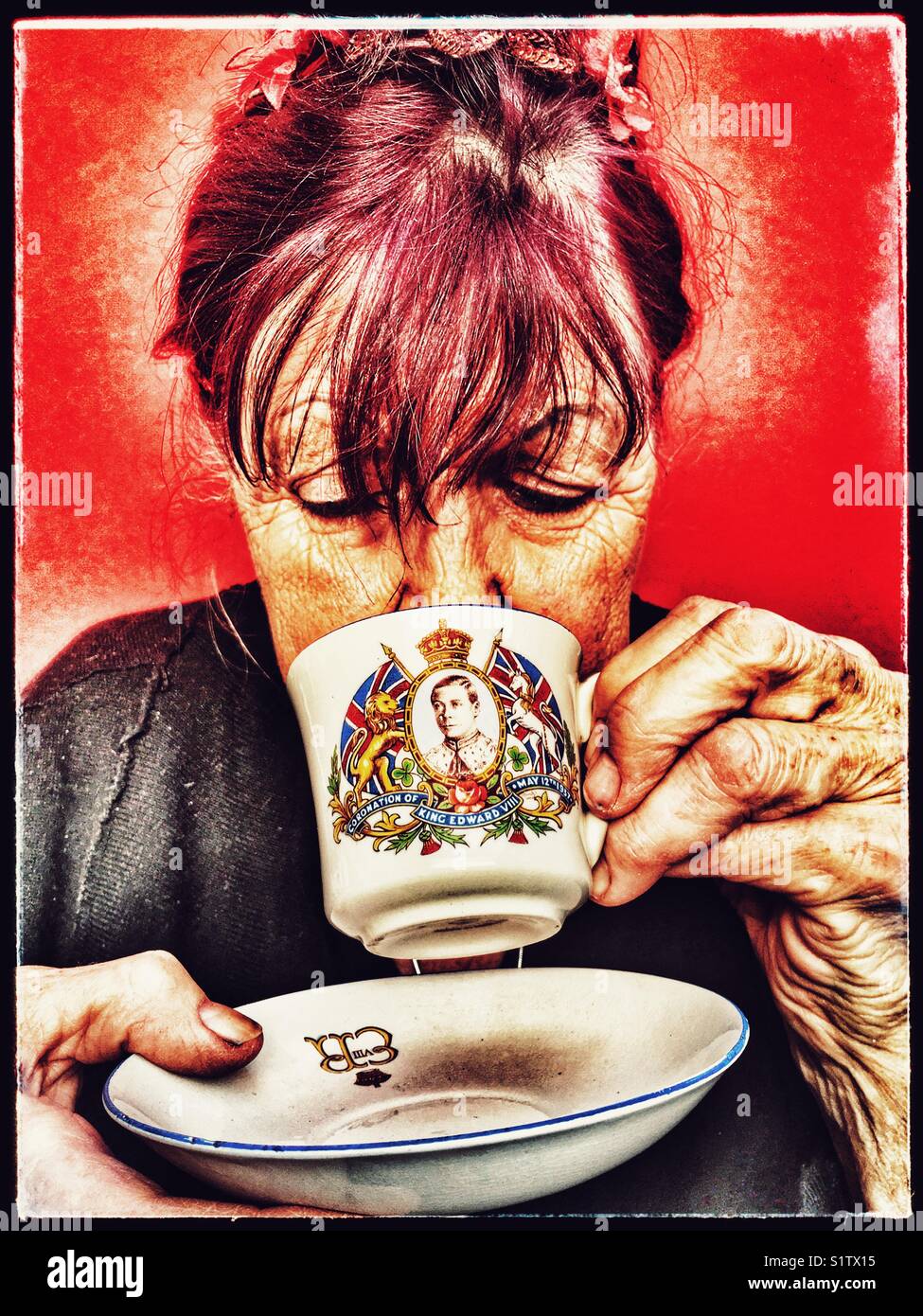 Elderly British woman drinking tea from Edward VIII coronation souvenir cup. - Smartphone Captured Stock Image