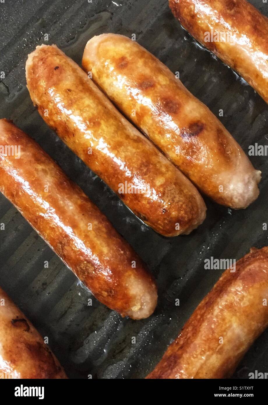 Frying sausages in a griddle pan Stock Photo Alamy