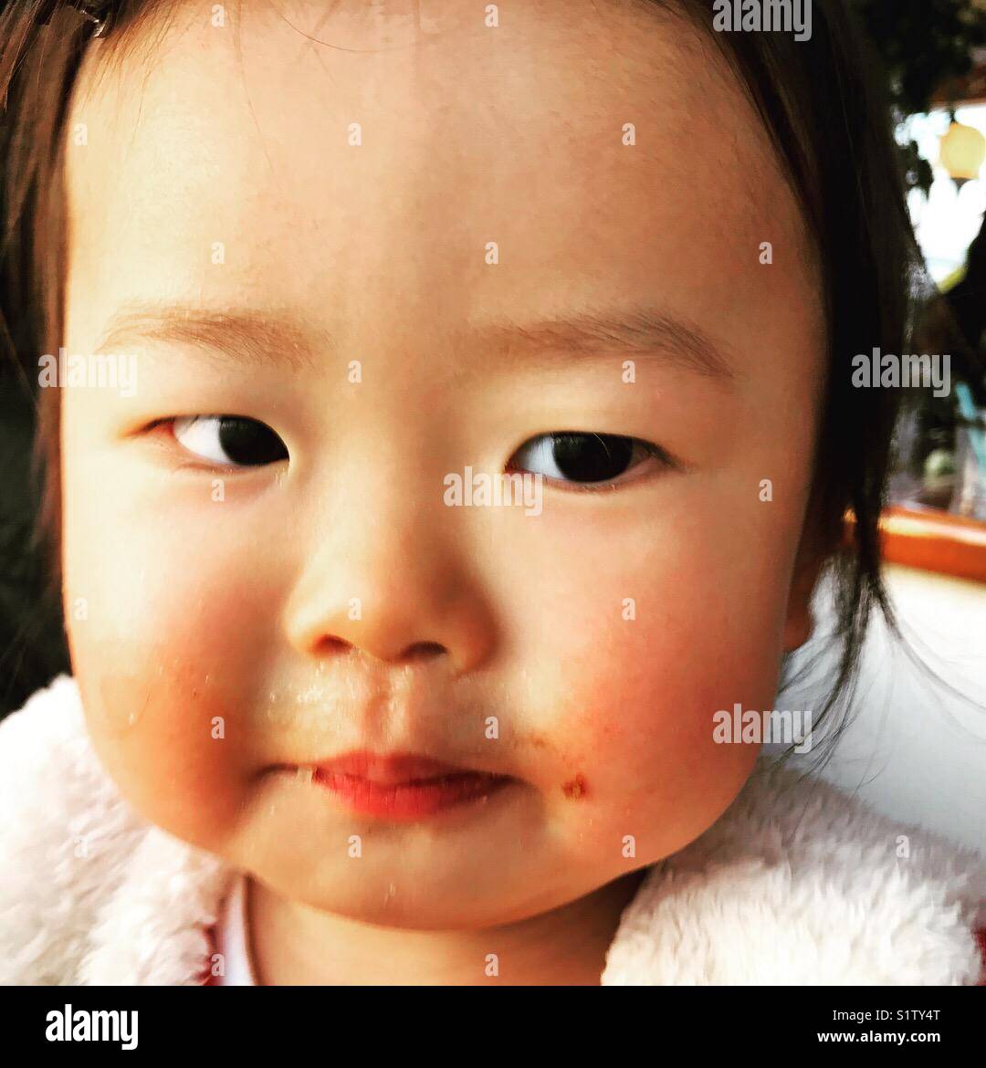 a japanese baby girl, 1 year old, with tomato sauce arornd her mouth Stock Photo