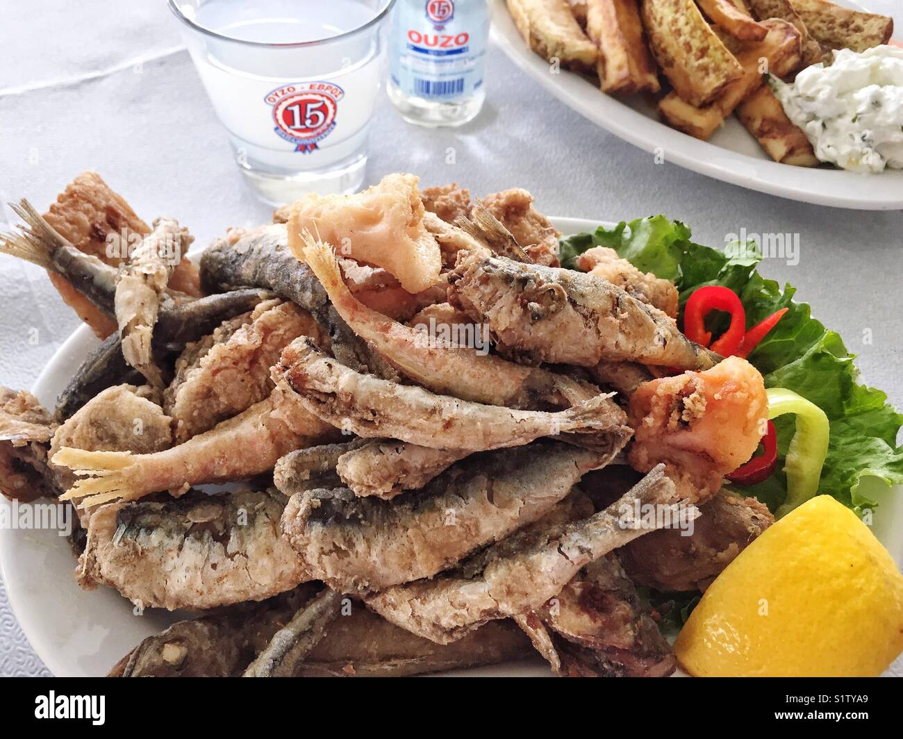 fried fish and greek drink, ouzo on table Stock Photo