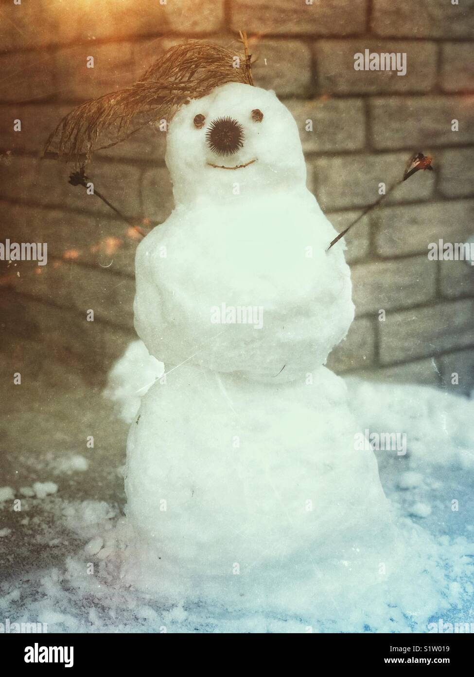 Small snowman on concrete step in front of grey brick house - Smartphone Captured Stock Image