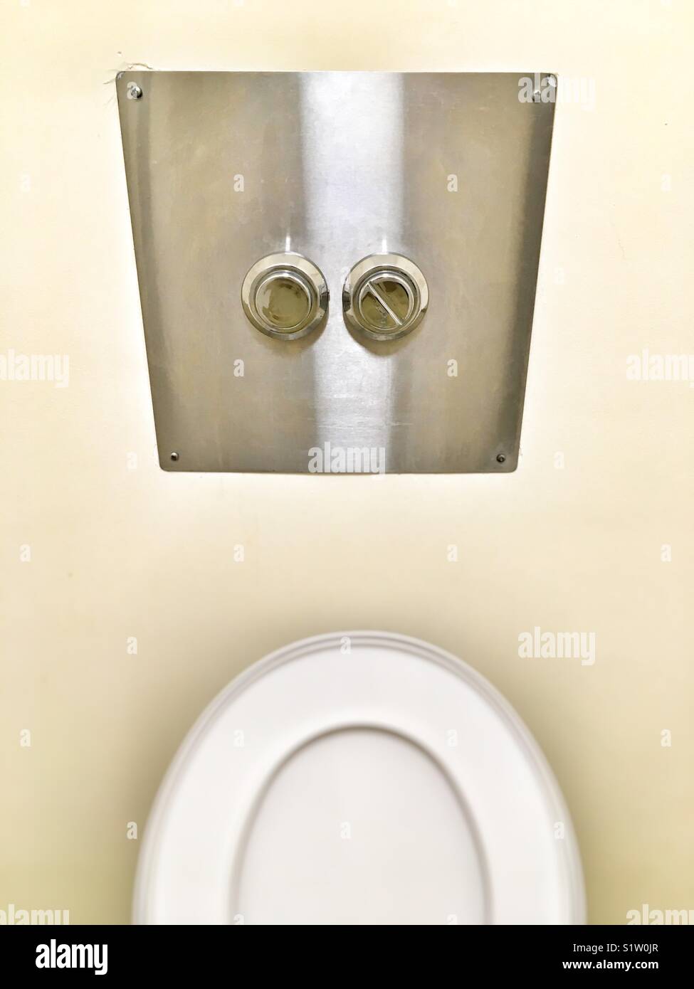 Flush buttons above a toilet seat. Stock Photo