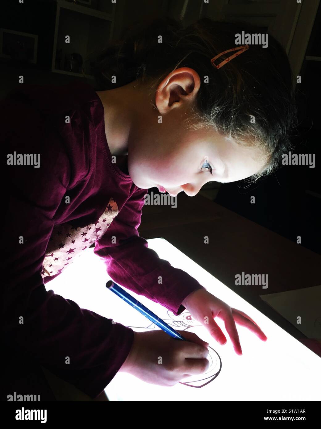 Little girl drawing on lightbox Stock Photo