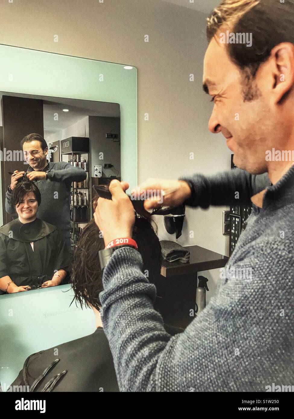 Male hairdresser cutting a young woman’s hair - Smartphone Captured Stock Image