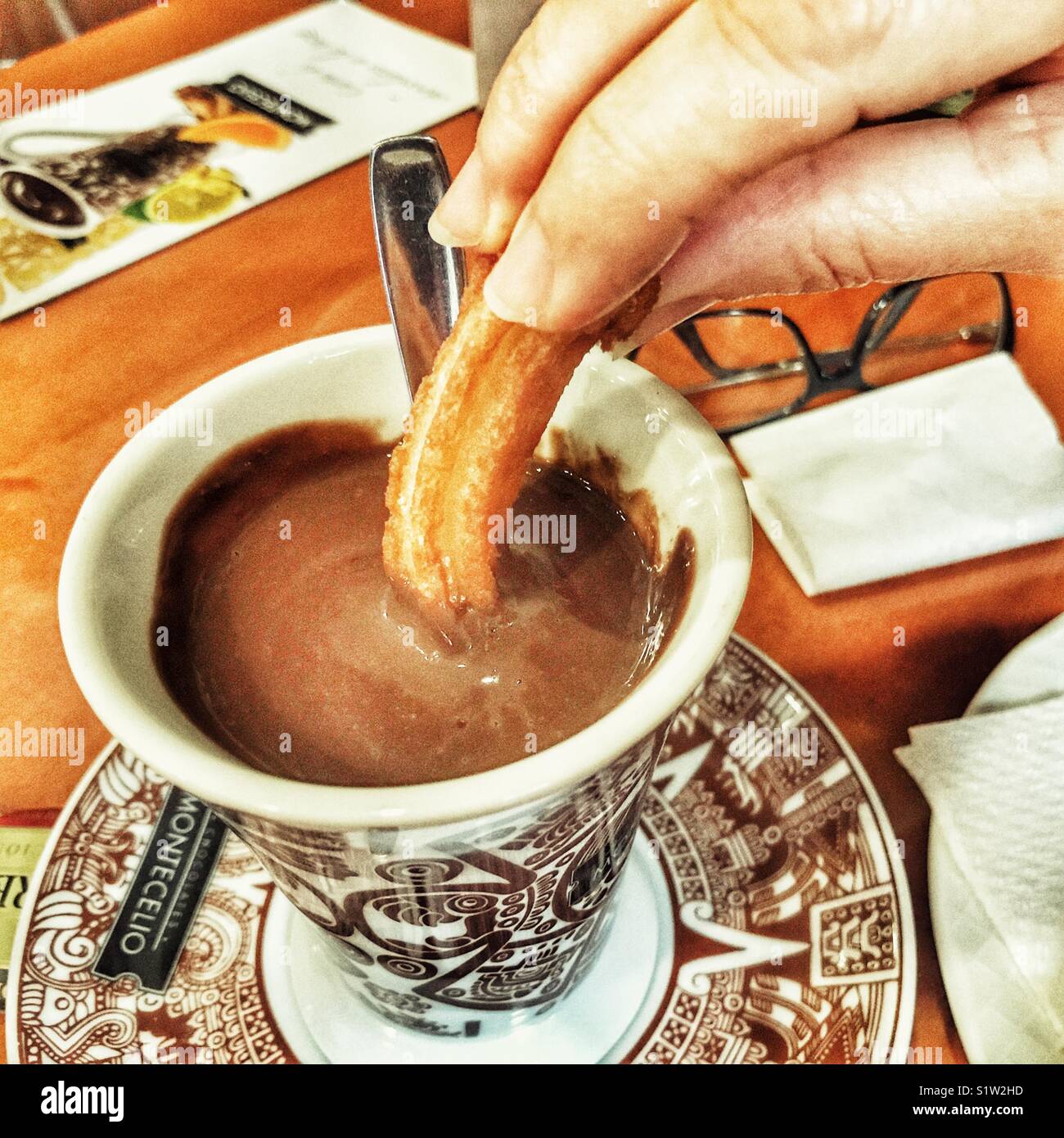 Dipping churros into a Montecello hot chocolate drink in a Spanish bar. - Smartphone Captured Stock Image