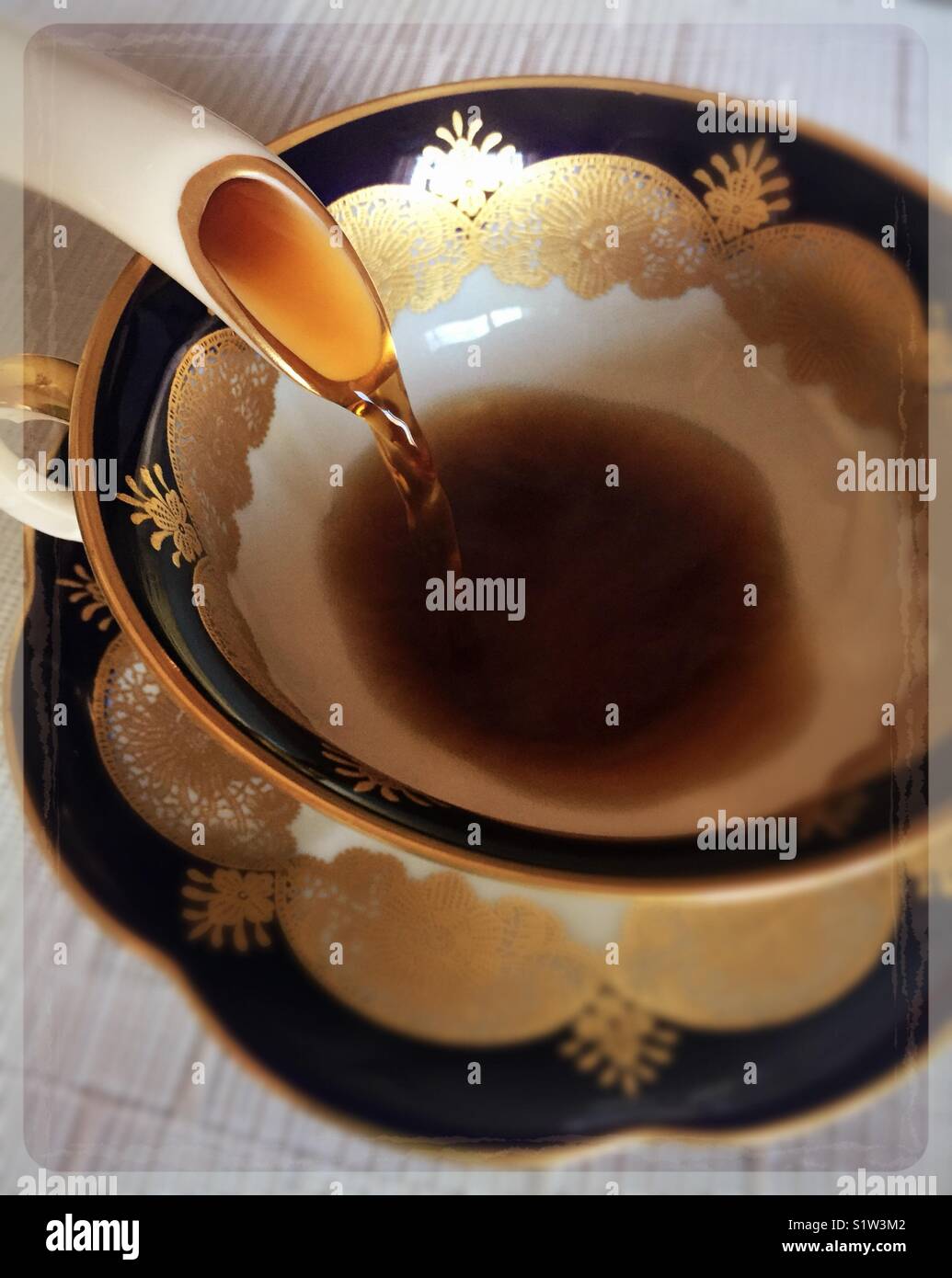 Coffee being poured from a china coffee pot into a china cup. - Smartphone Captured Stock Image