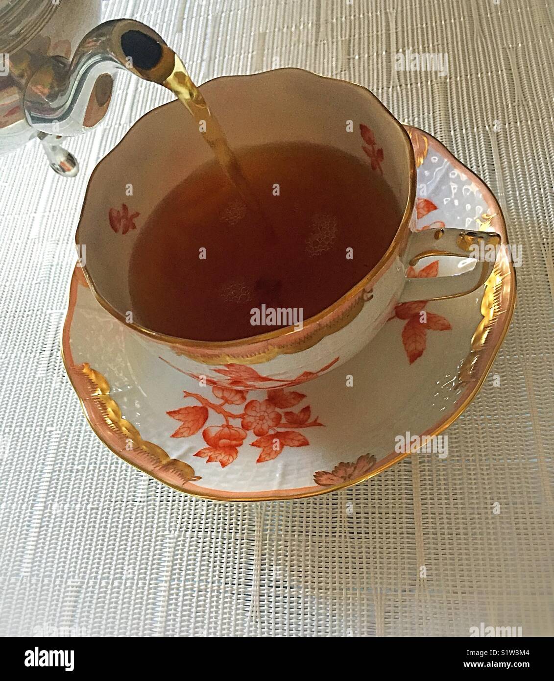 Pouring hot tea from s pewter teapot into a fancy porcelain teacup Stock Photo Alamy