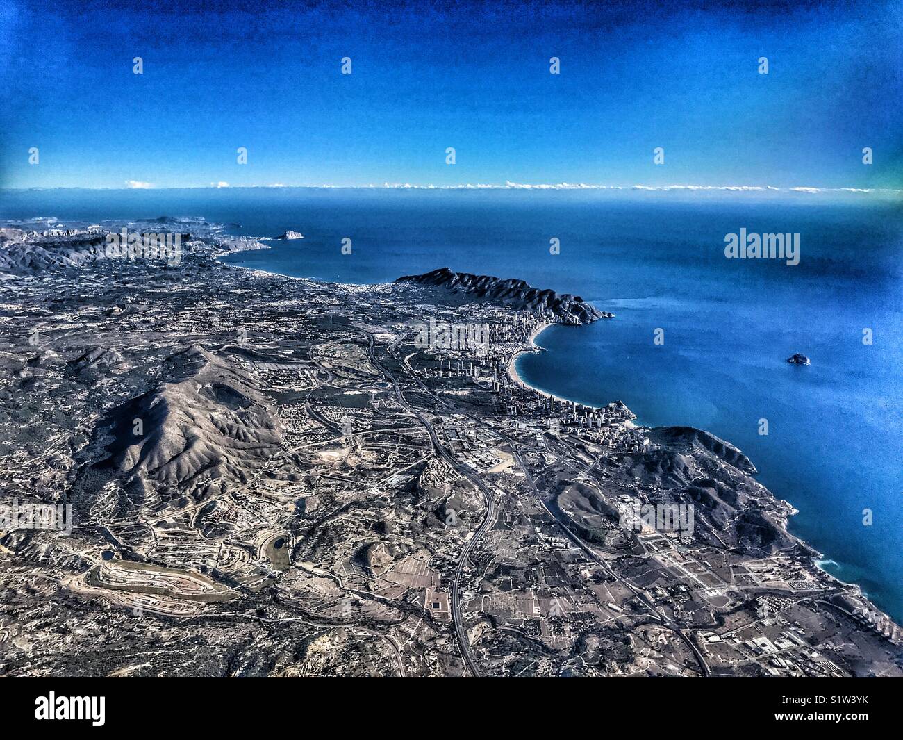 View from aeroplane. Flying over the Costa Blanca, Spain with the skyscrapers of coastal resort town of Benidorm clearly visible, plus in the distance Calpe, then Montgo mountain & Javea. - Smartphone Captured Stock Image