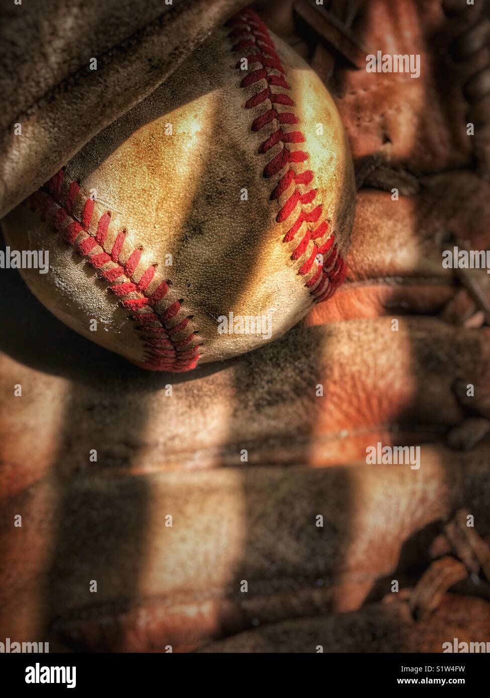 Weathered baseball in old glove Stock Photo