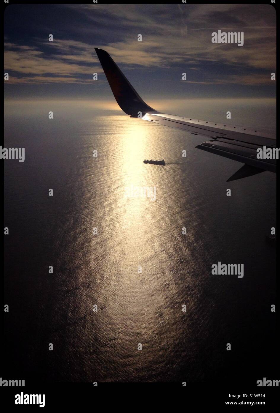 A container ship in the Mediterranean is highlighted by the sunrise as seen from a Jet2 flight en-route to Spain. - Smartphone Captured Stock Image