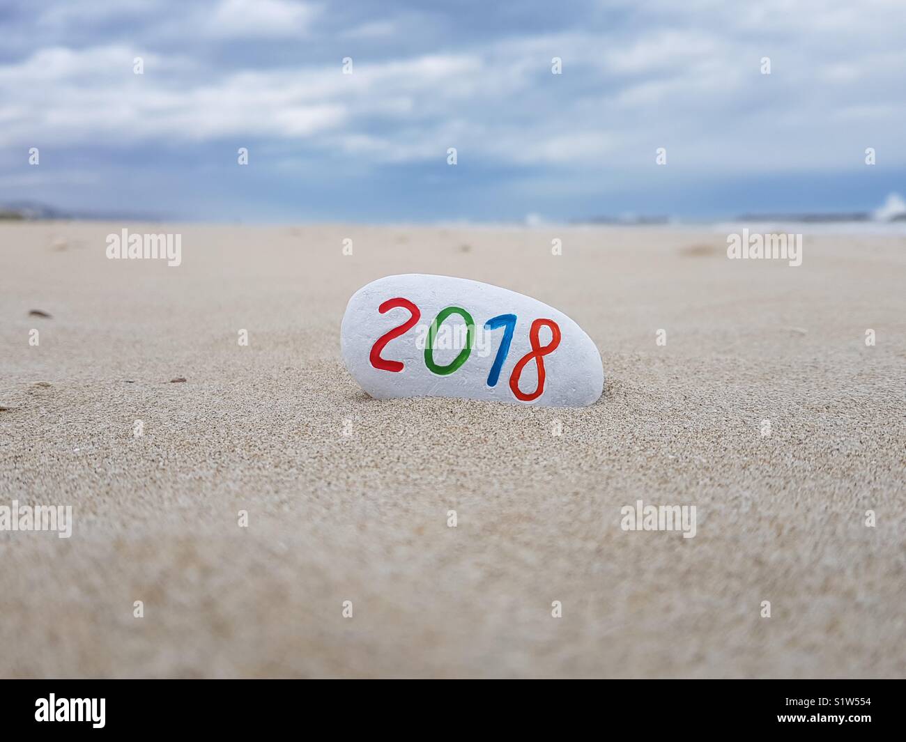 2018 new year painted on a stone with beach background - Smartphone Captured Stock Image