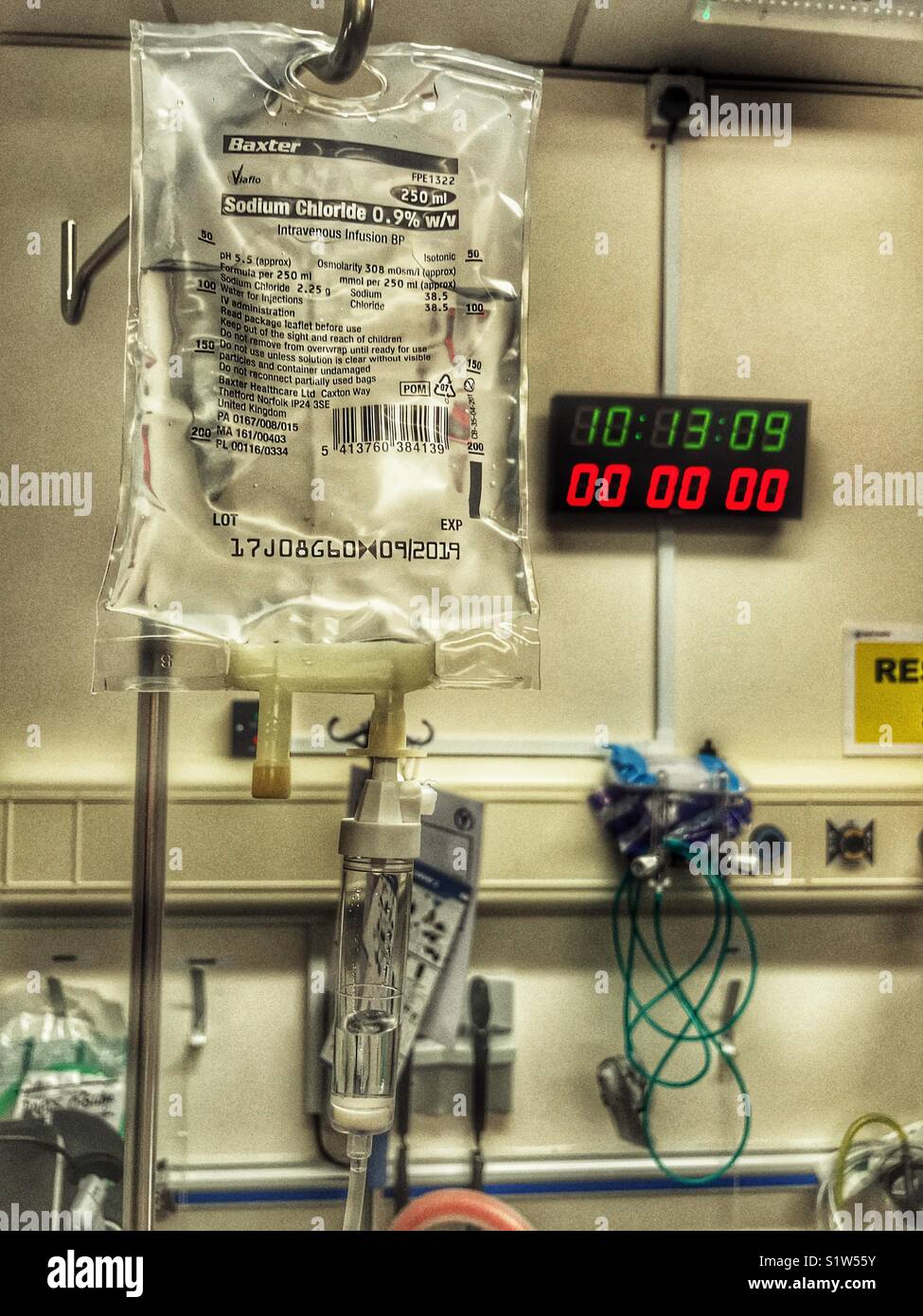 Bag of sodium chloride solution on a drip stand being administered in an NHS hospital. - Smartphone Captured Stock Image