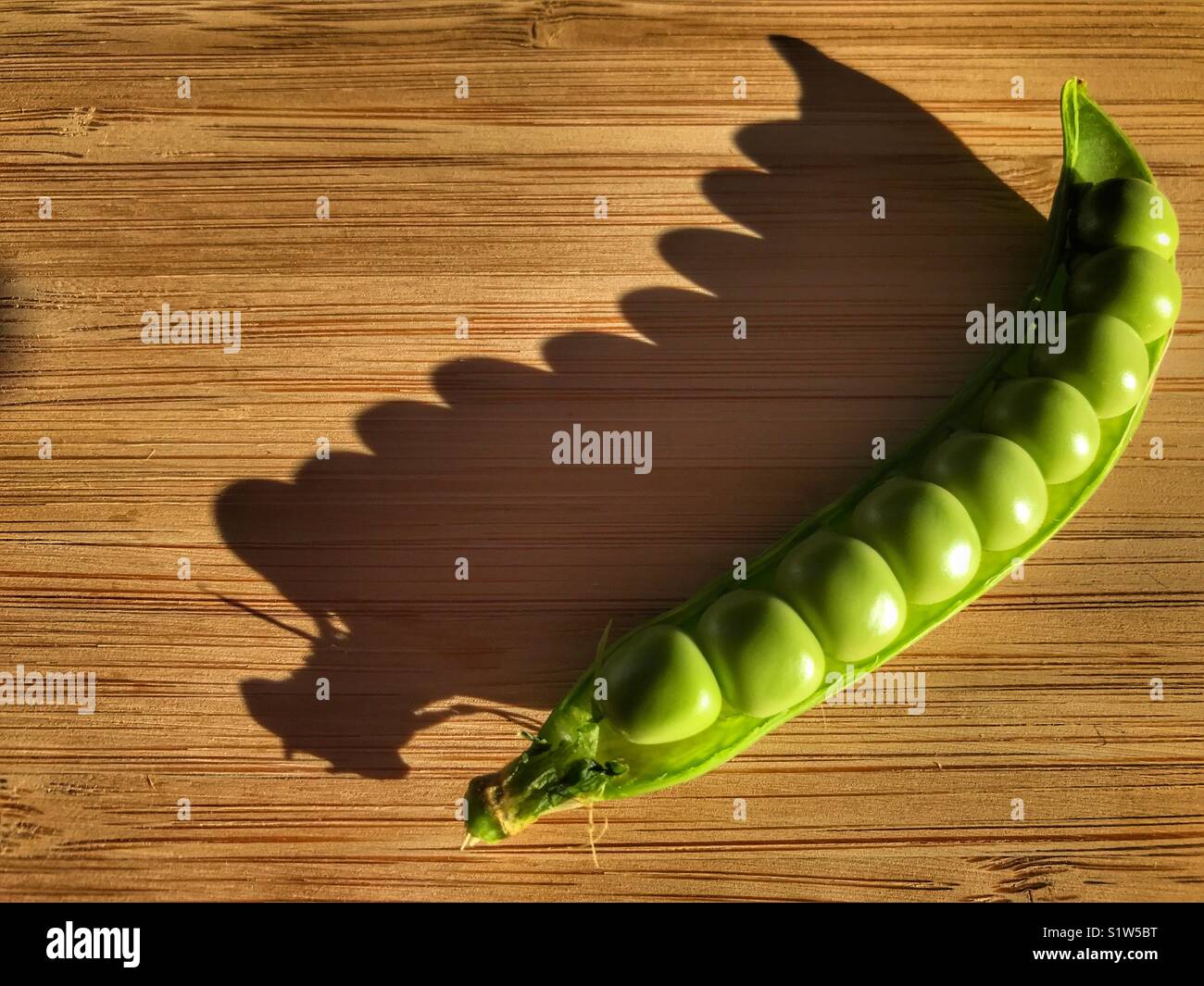 Fresh green peas in a pod on a bamboo board - Smartphone Captured Stock Image