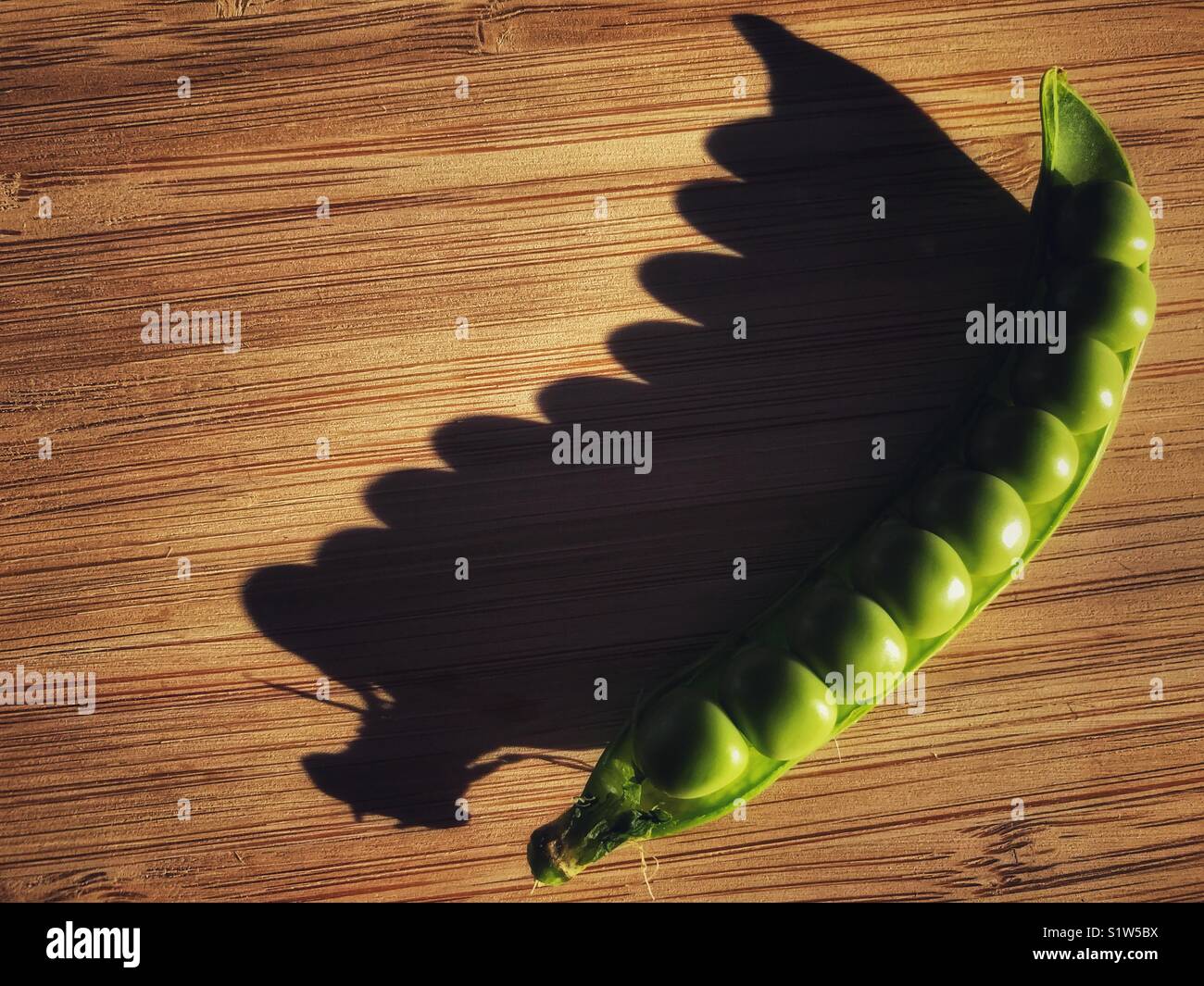 Fresh green peas in a pod on a bamboo board - Smartphone Captured Stock Image