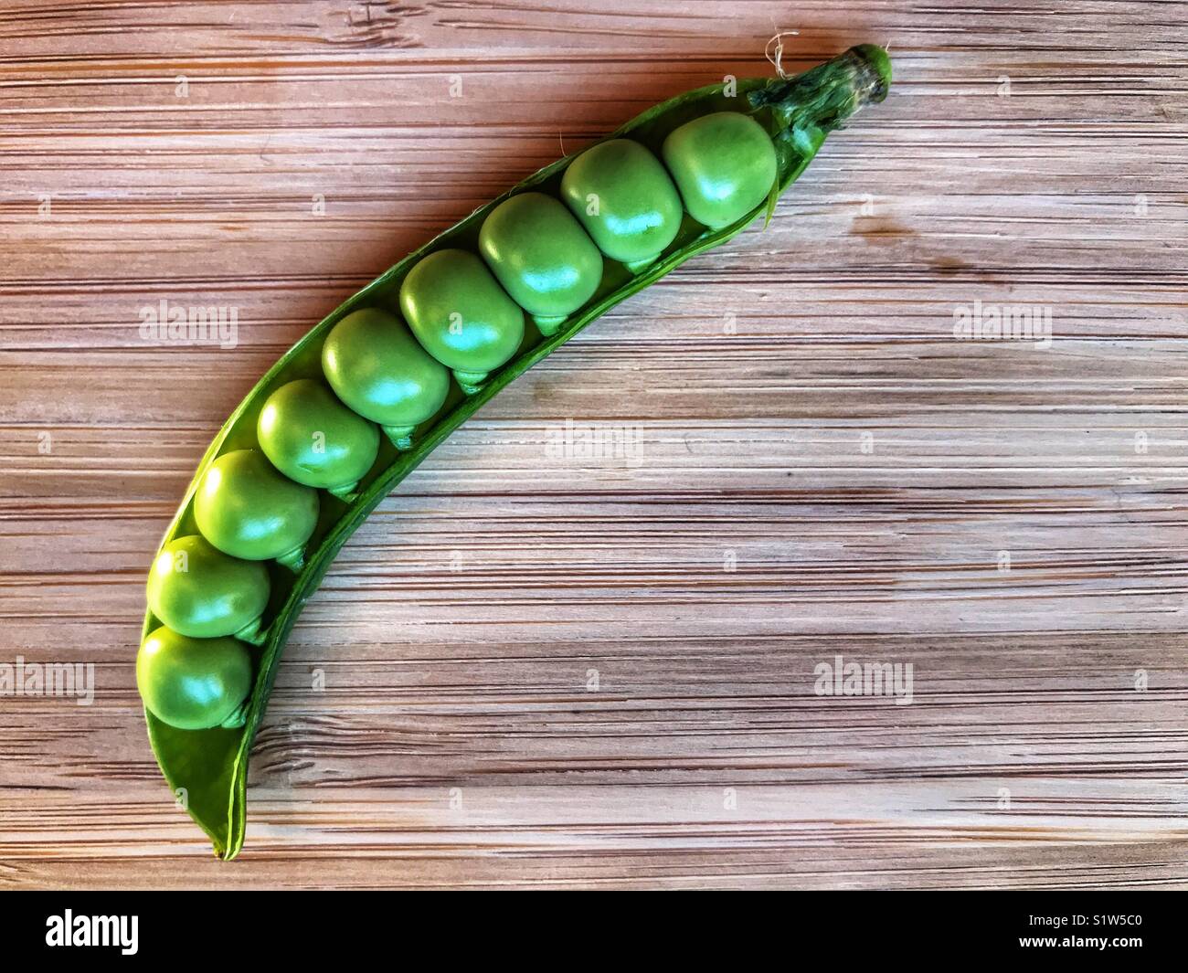 Fresh green peas in a pod on a bamboo board with copy space - Smartphone Captured Stock Image